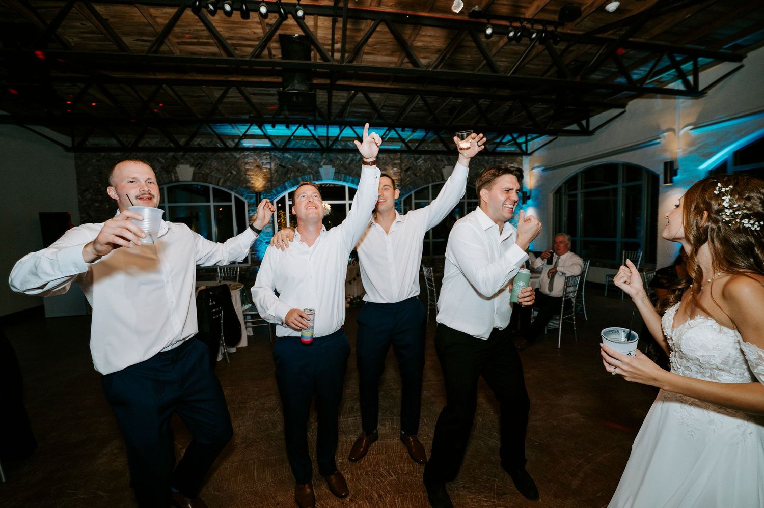 Wedding reception dance party in a dark venue with energetic dancing and celebration.