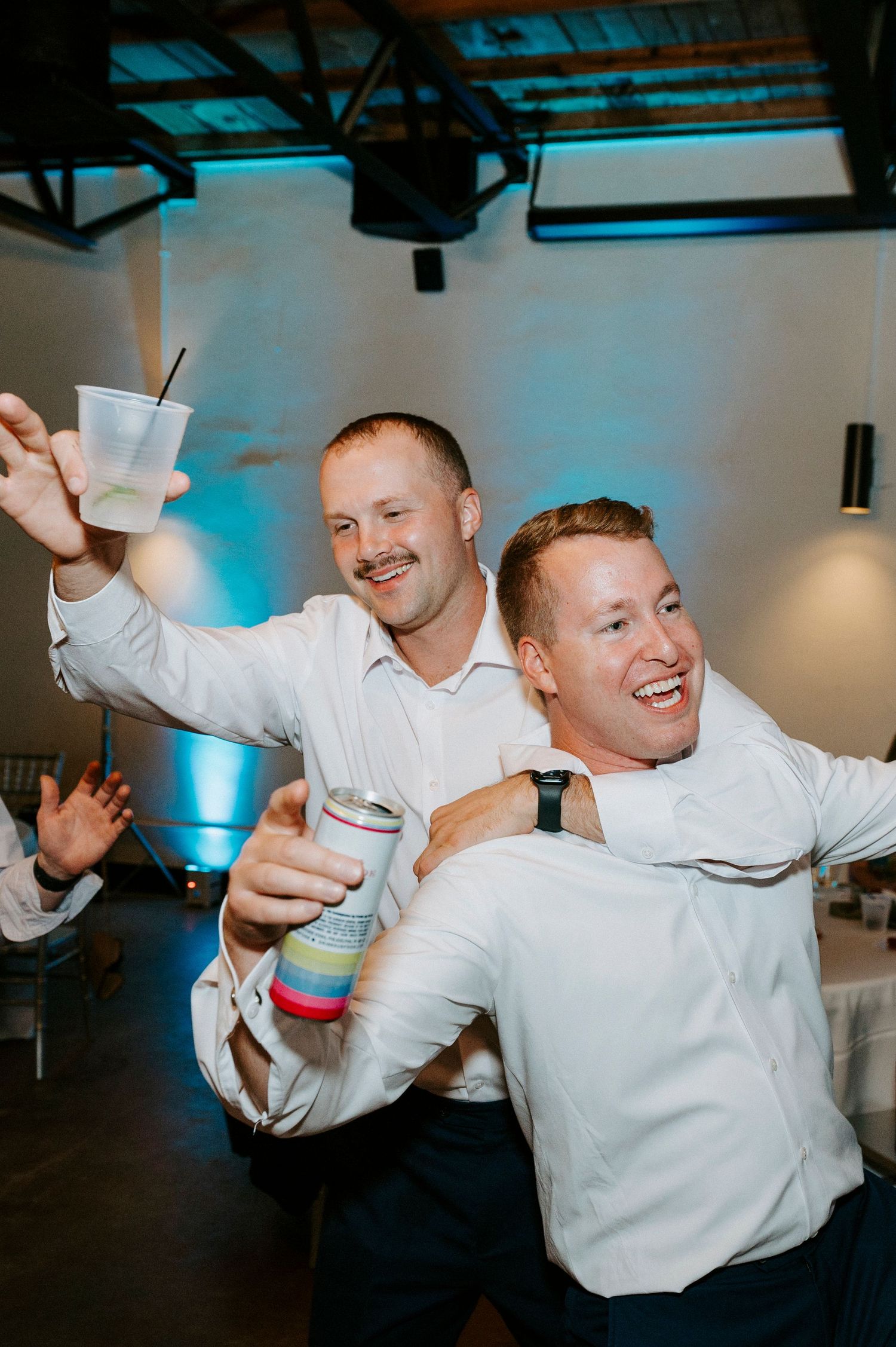Wedding celebration on dance floor with party guests in white shirts dancing energetically.