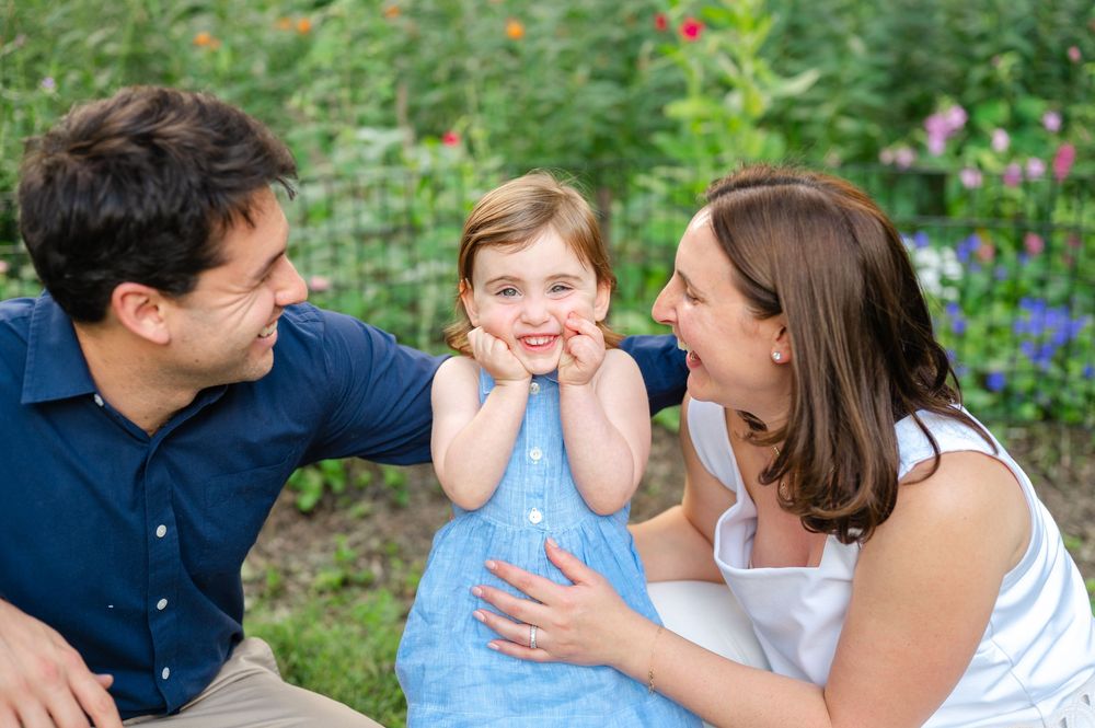 Lifestyle family photography with parents smiling at their toddler in Central Park.