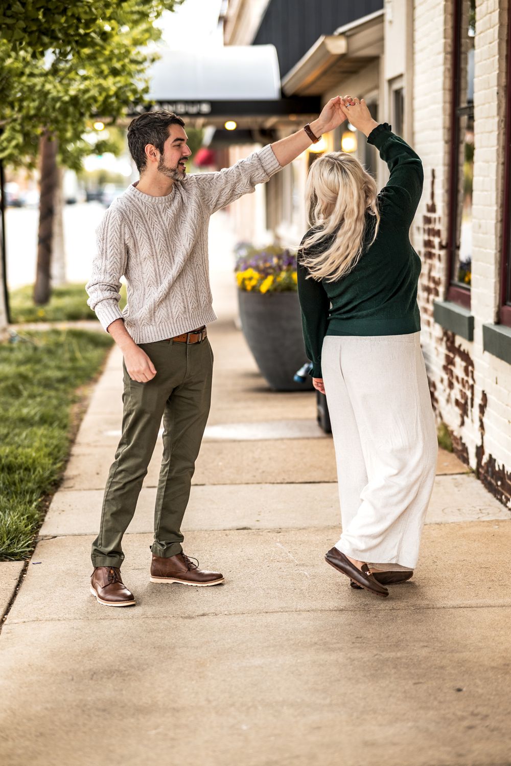 A couple dances together on a sidewalk in front of a building, captured in a series of romantic movement shots.