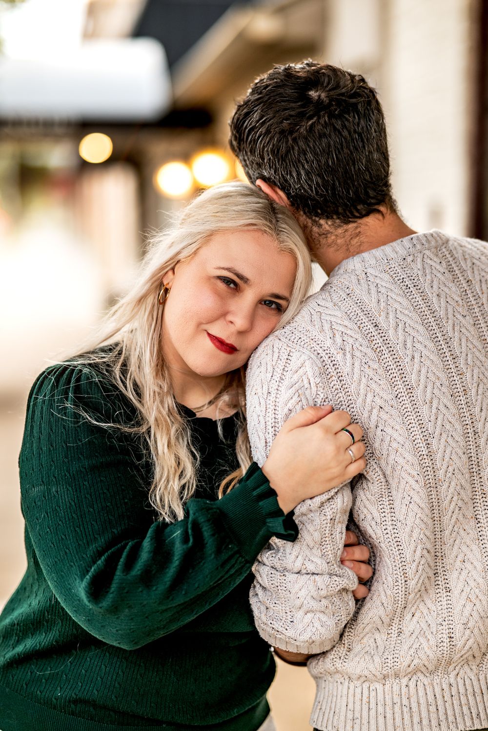 A couple shares an intimate moment in a series of photos, with one wearing emerald green and the other in a cream sweater.
