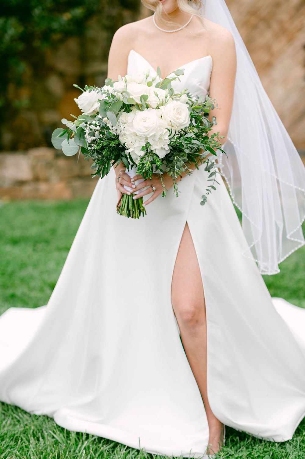 White wedding dress details showing elegant flowy fabric and romantic bridal bouquets with fresh greenery and white flowers.