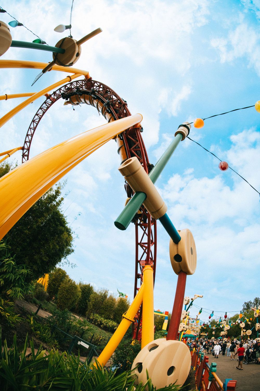 Colorful theme park ride with giant toy-like elements including propellers and musical instruments against a blue sky.