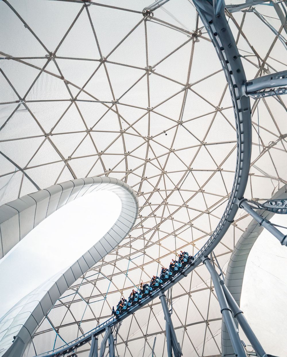 Geometric dome structure with a roller coaster track winding through its modern architectural design.