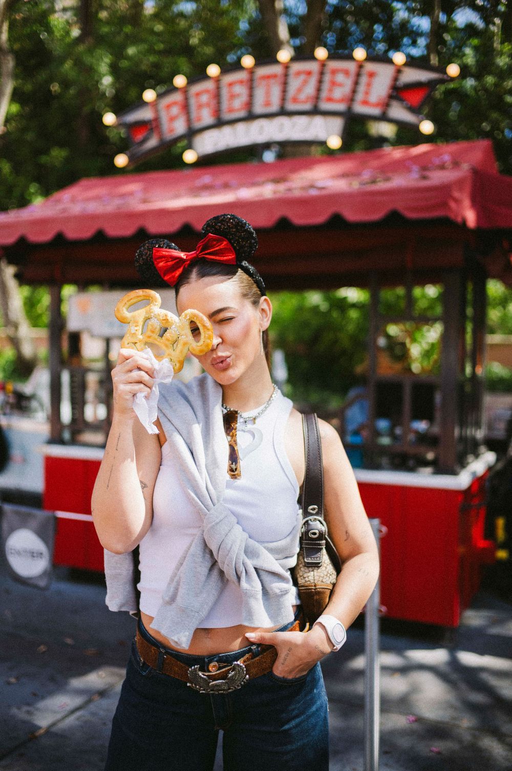 A series of photos showing someone eating a hot dog at an outdoor food stand with red umbrellas in the background.