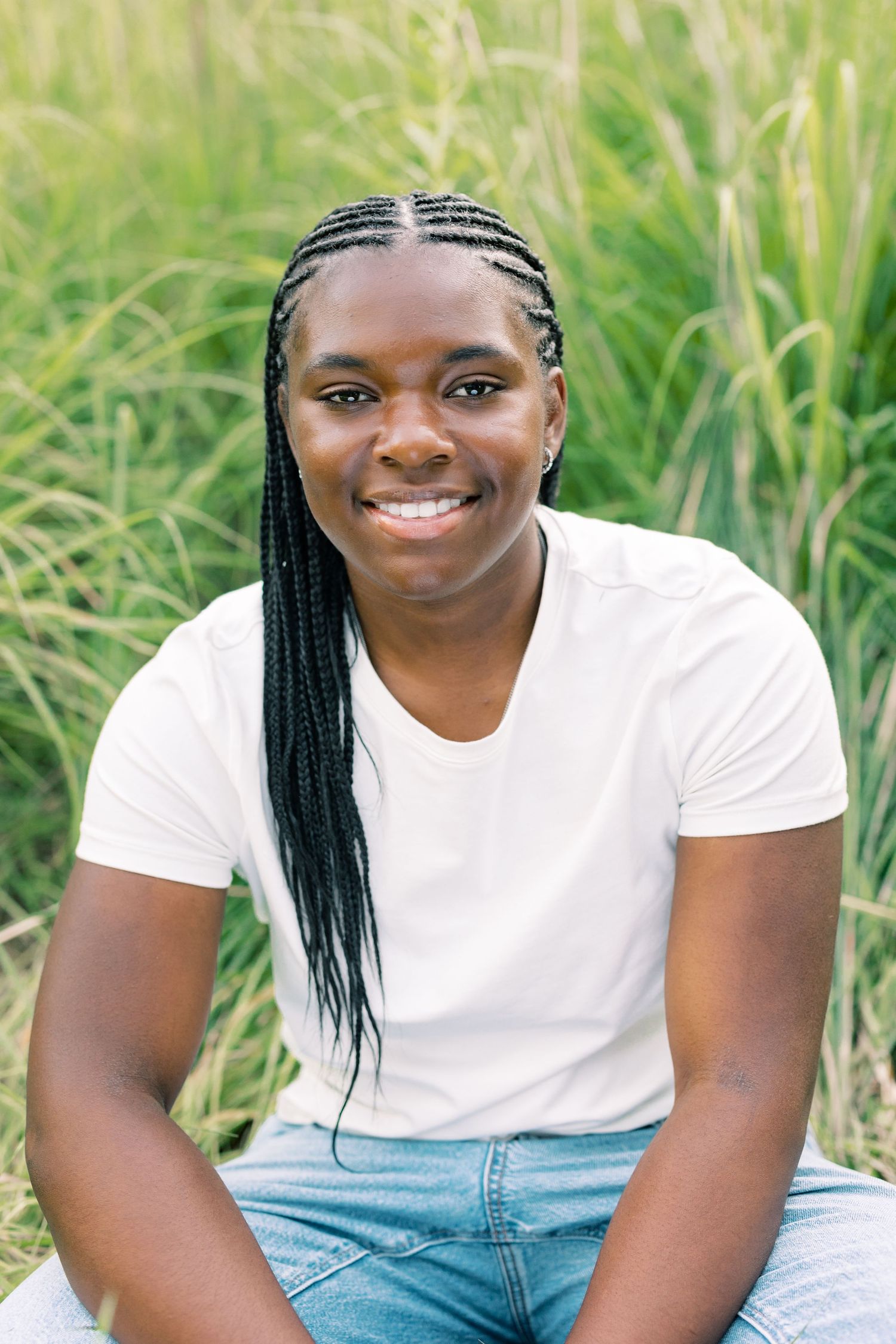 A summer portrait session in tall grass featuring a white t-shirt and denim jeans outfit.