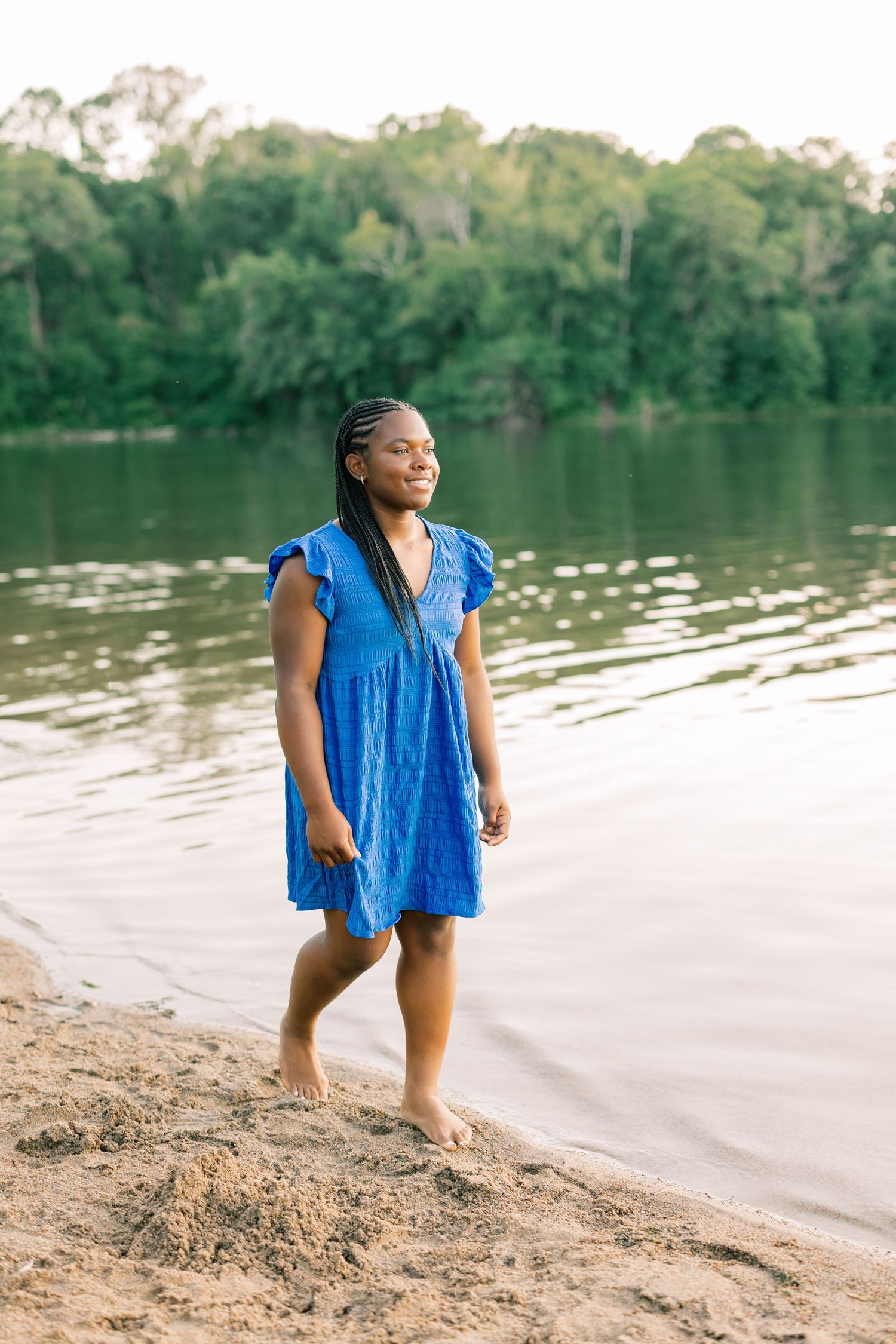 Person wearing a bright blue shirt enjoys a peaceful day near a calm lake shoreline in nature.