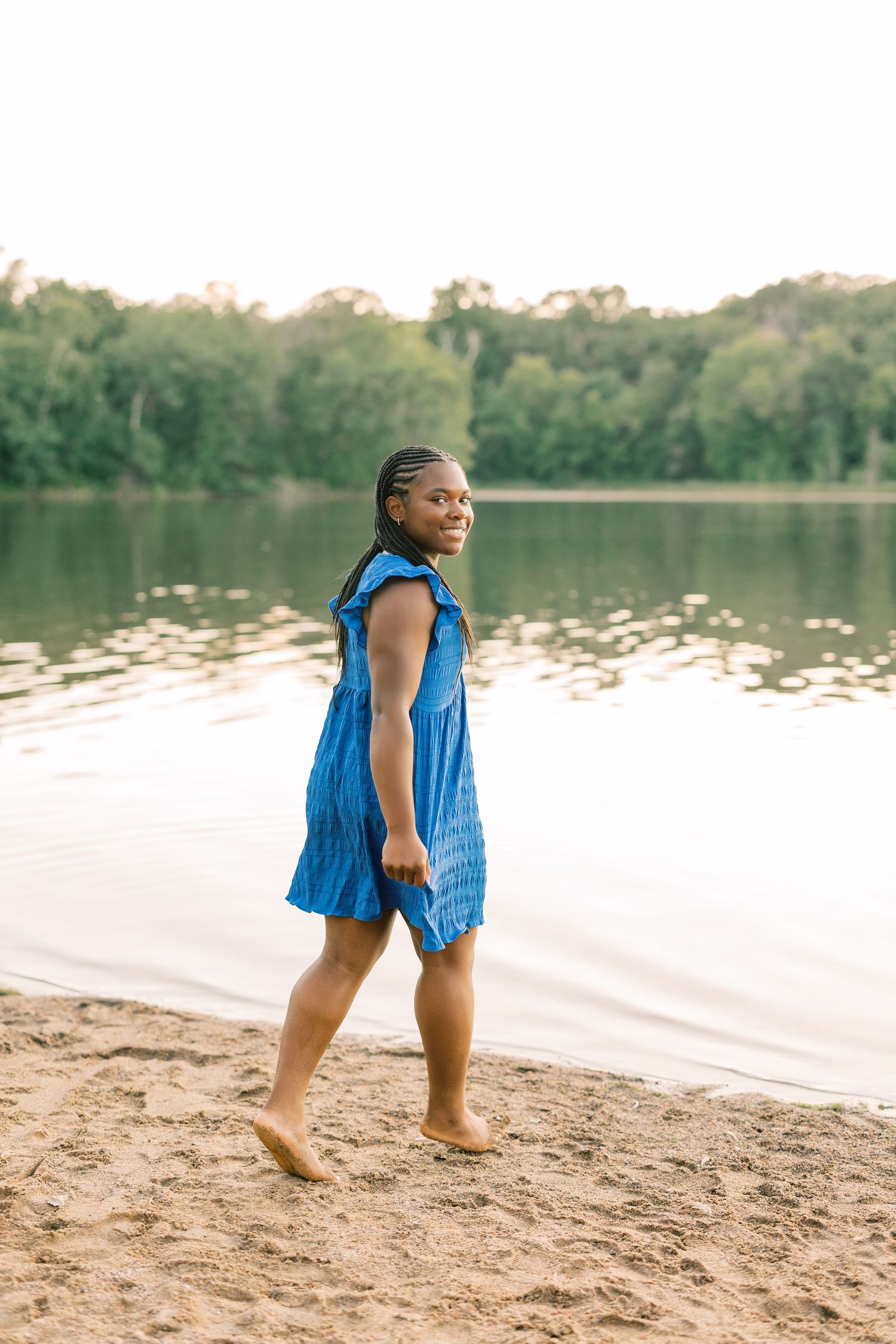 Multiple views of someone playing and walking along a sandy lakeshore in a vibrant blue sleeveless top.