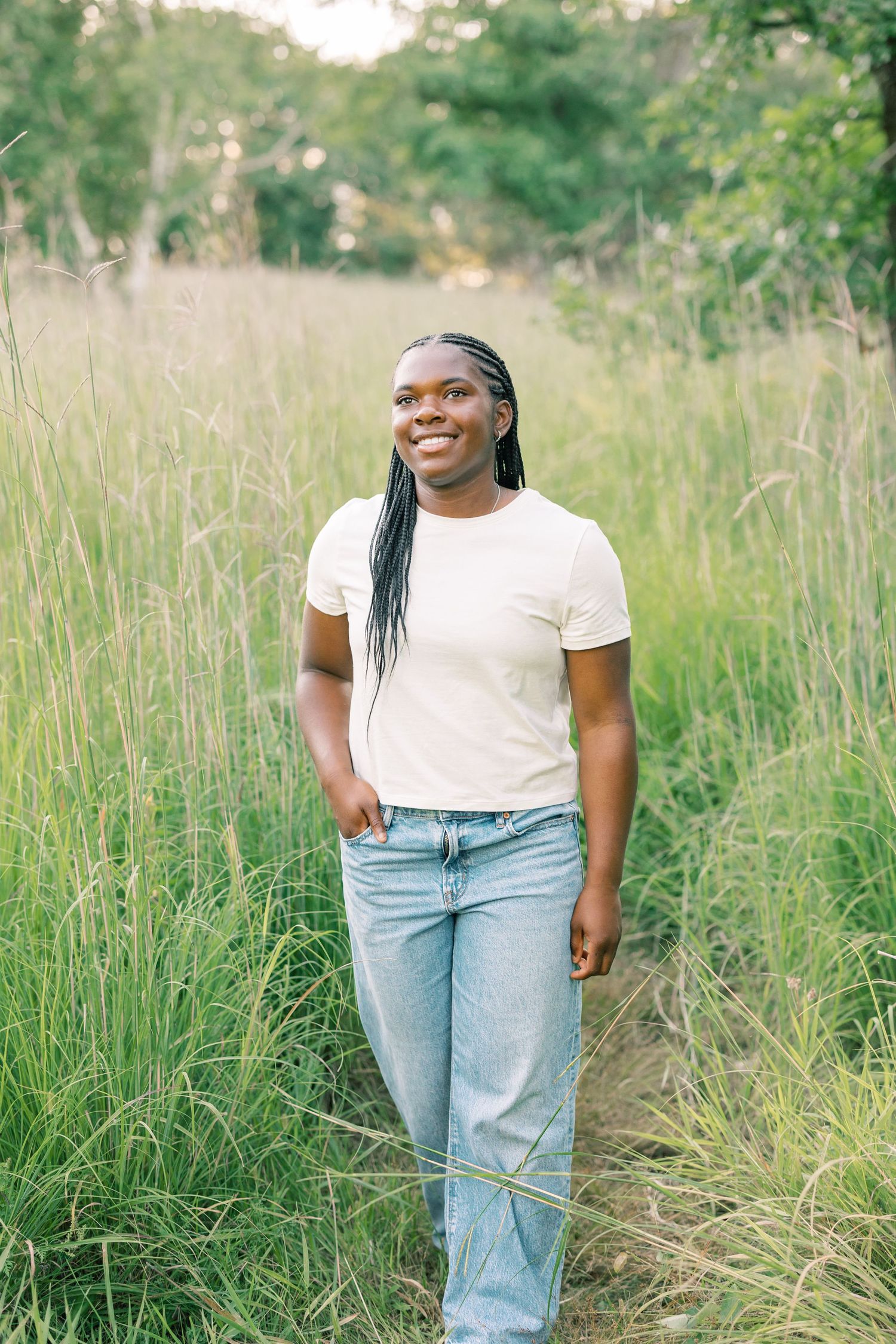 Casual outdoor portrait poses in tall grass wearing light denim jeans and white top on a sunny day.