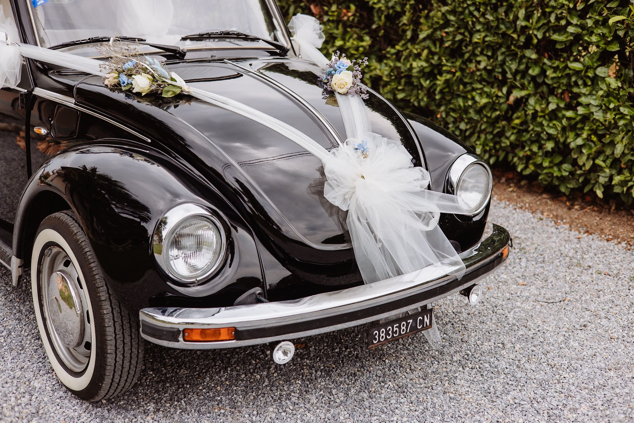 Classic black and silver vintage Porsche cars decorated with wedding flowers parked on a gravel driveway.