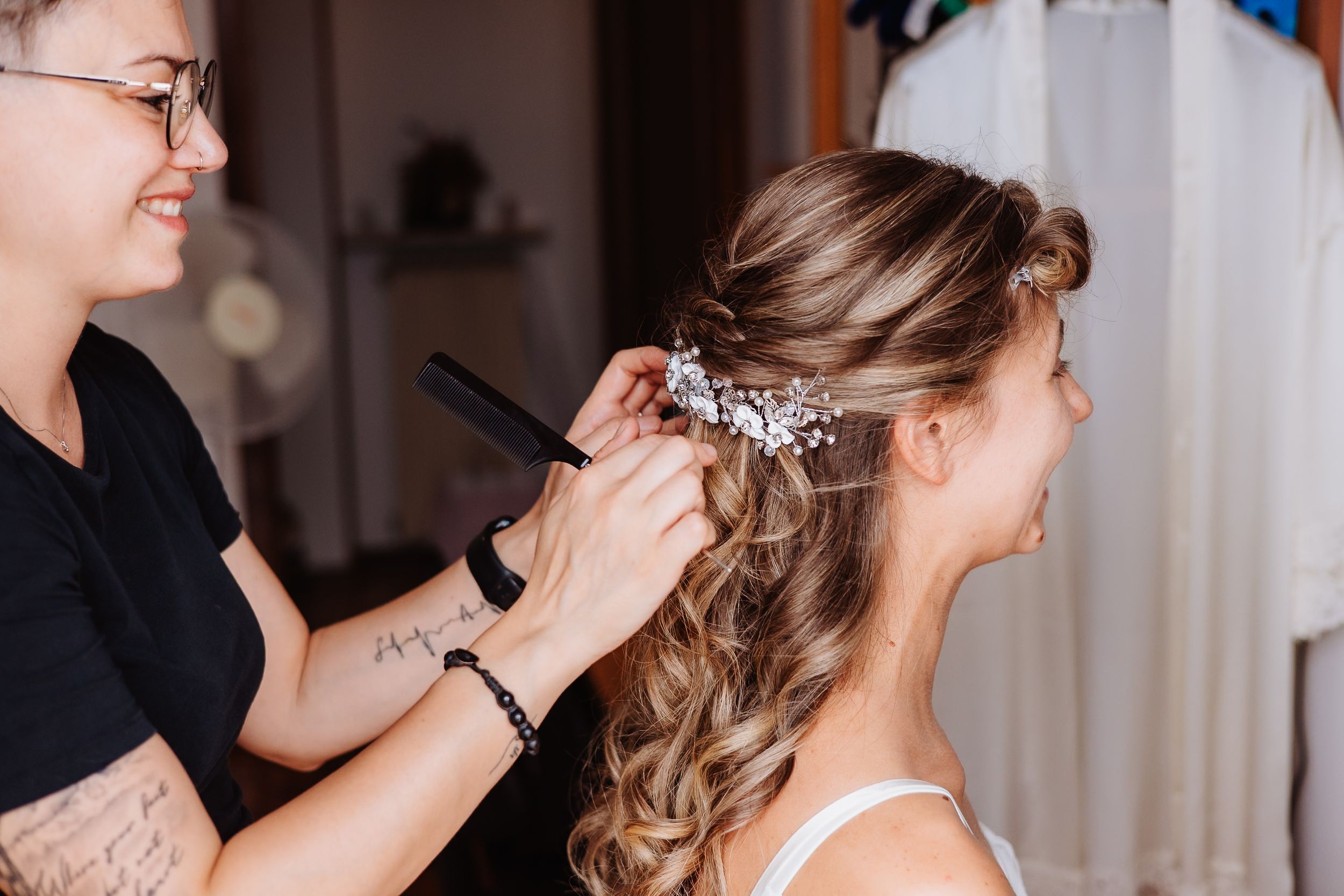 A bride gets her hair styled and decorated with delicate floral accessories during wedding preparations.