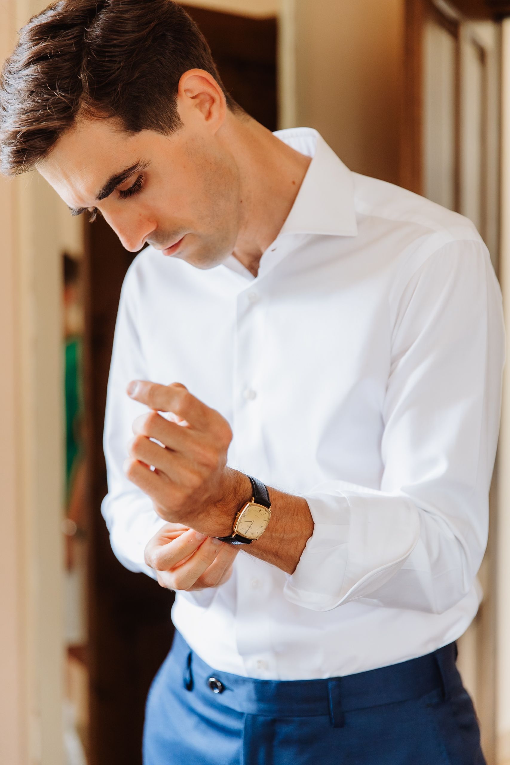 A person in a white sweater and blue jeans wipes their nose with a tissue or handkerchief.
