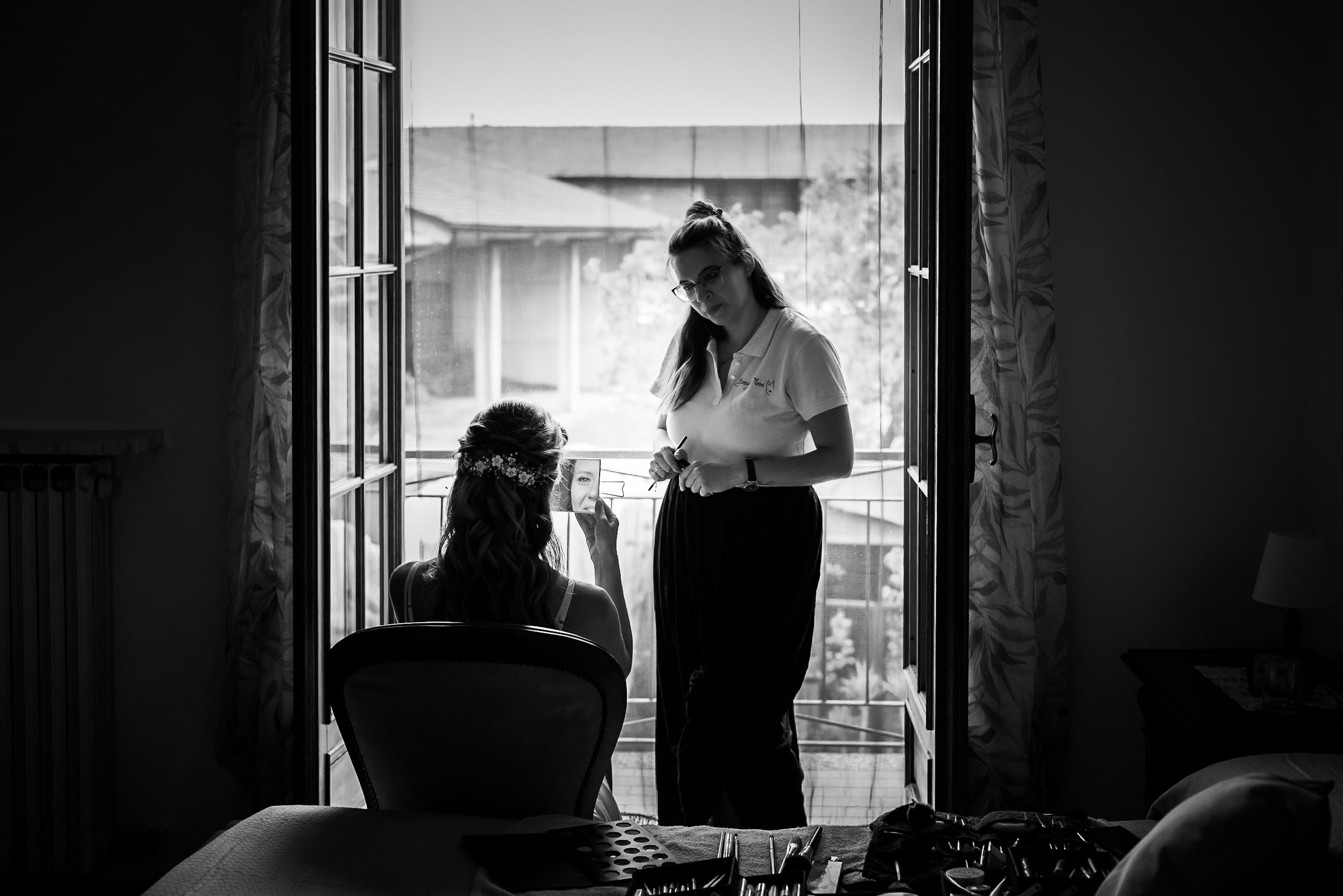 A silhouetted figure is visible through a window in a moody black and white photograph.