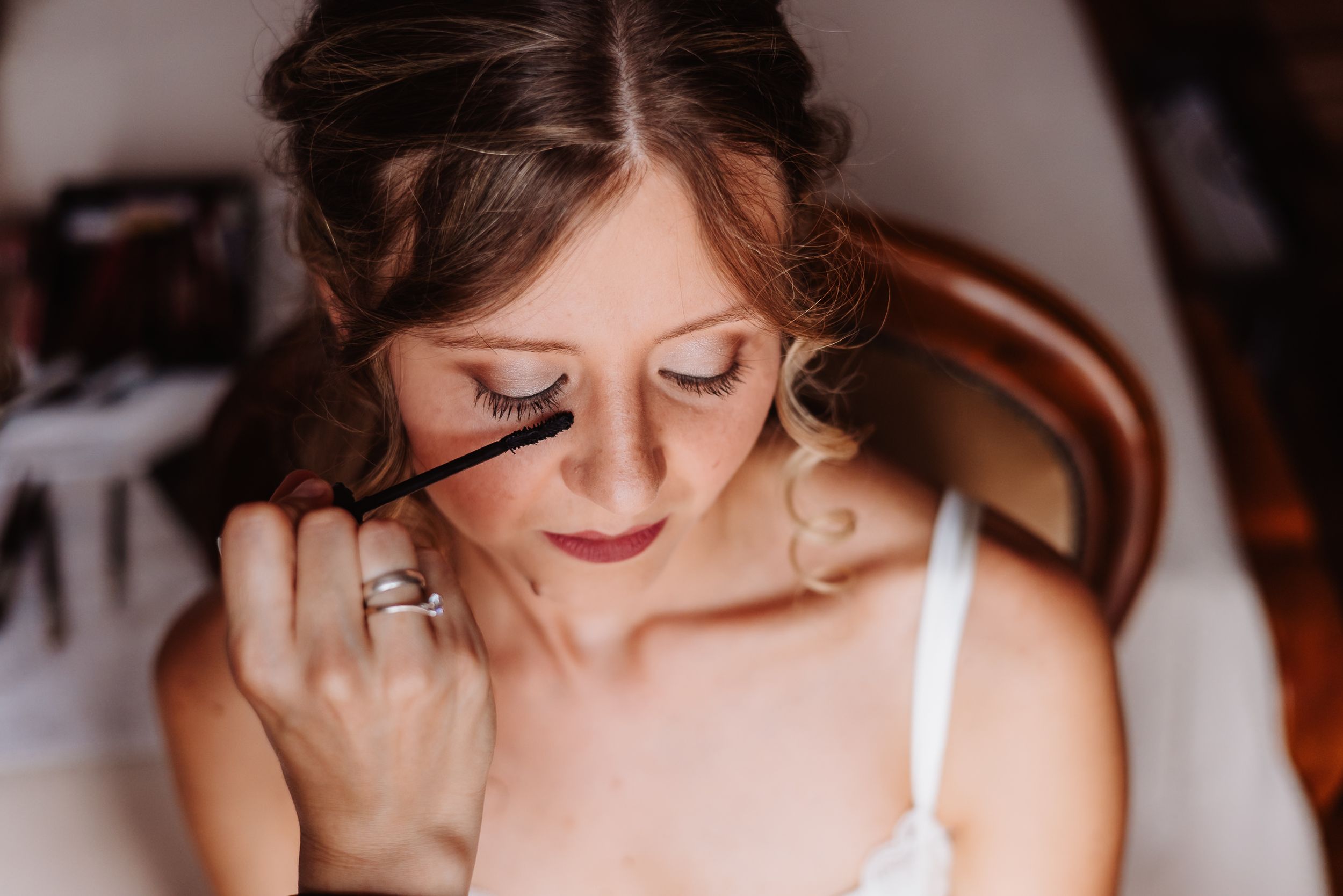 Macro shot of someone with eyes closed and artistic eyelash extensions wearing shimmering bridal makeup.