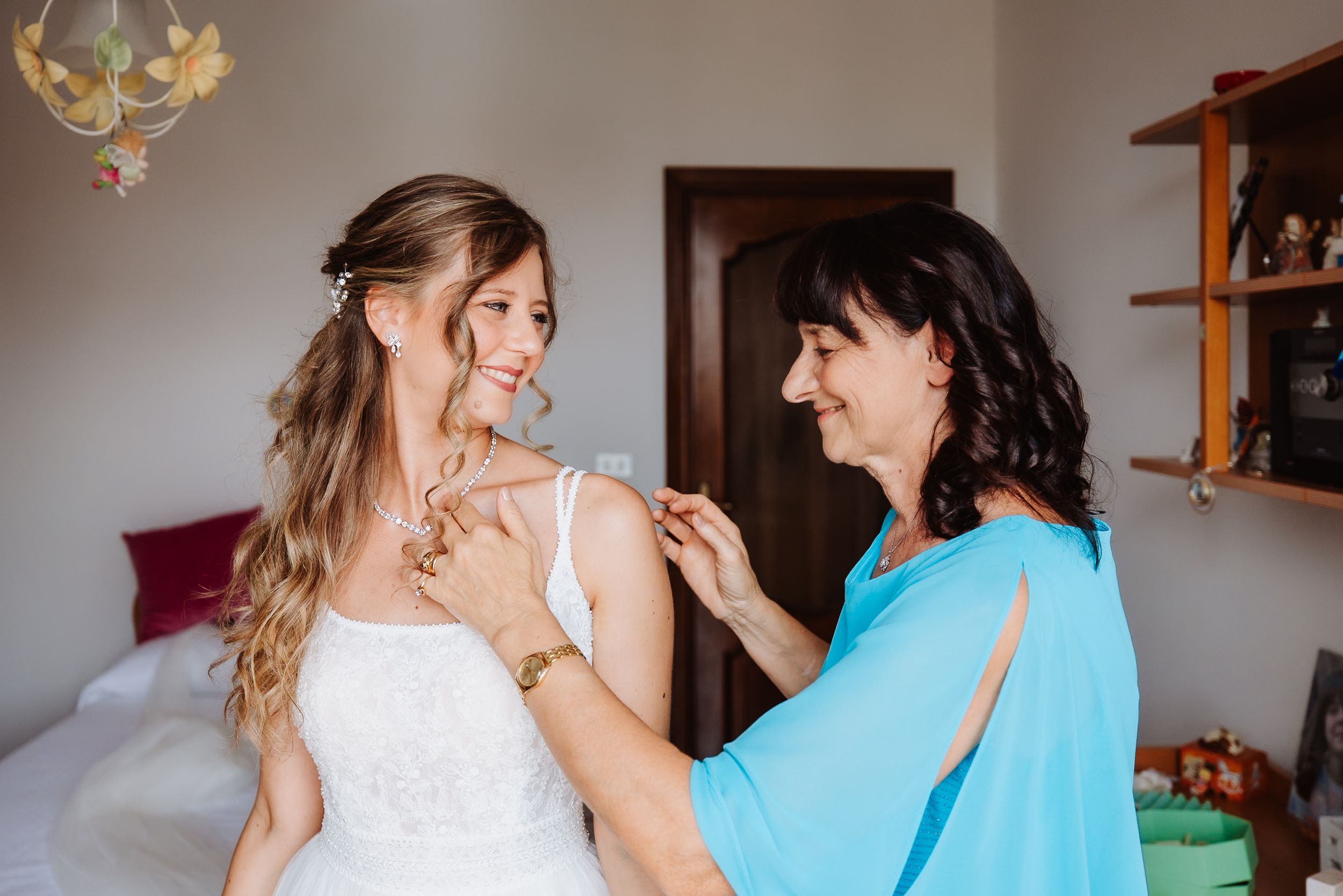 A heartfelt moment between people in a light blue dress and white wedding gown embracing.