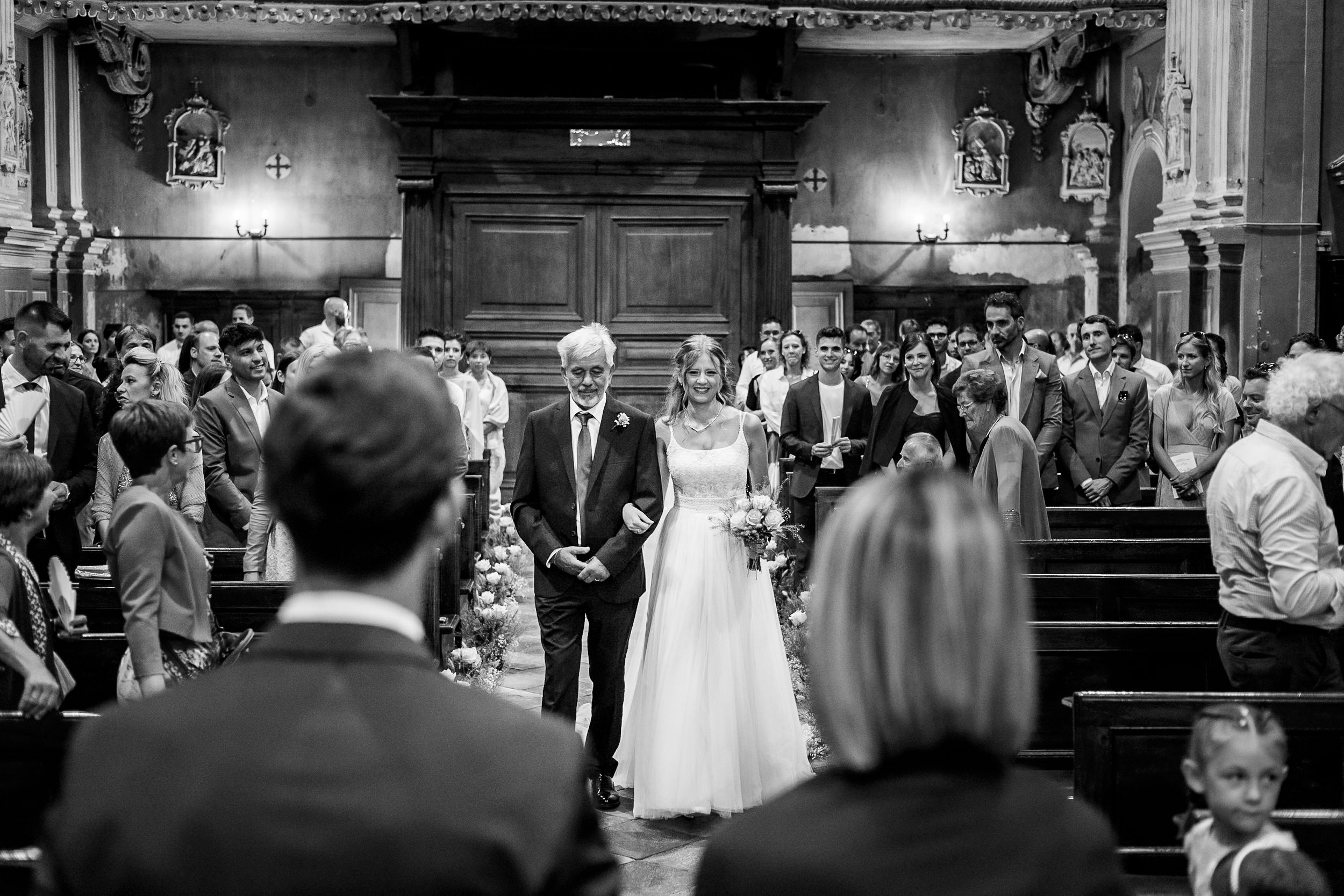 The newlywed couple exits the church while guests line either side to watch the festive recessional procession.