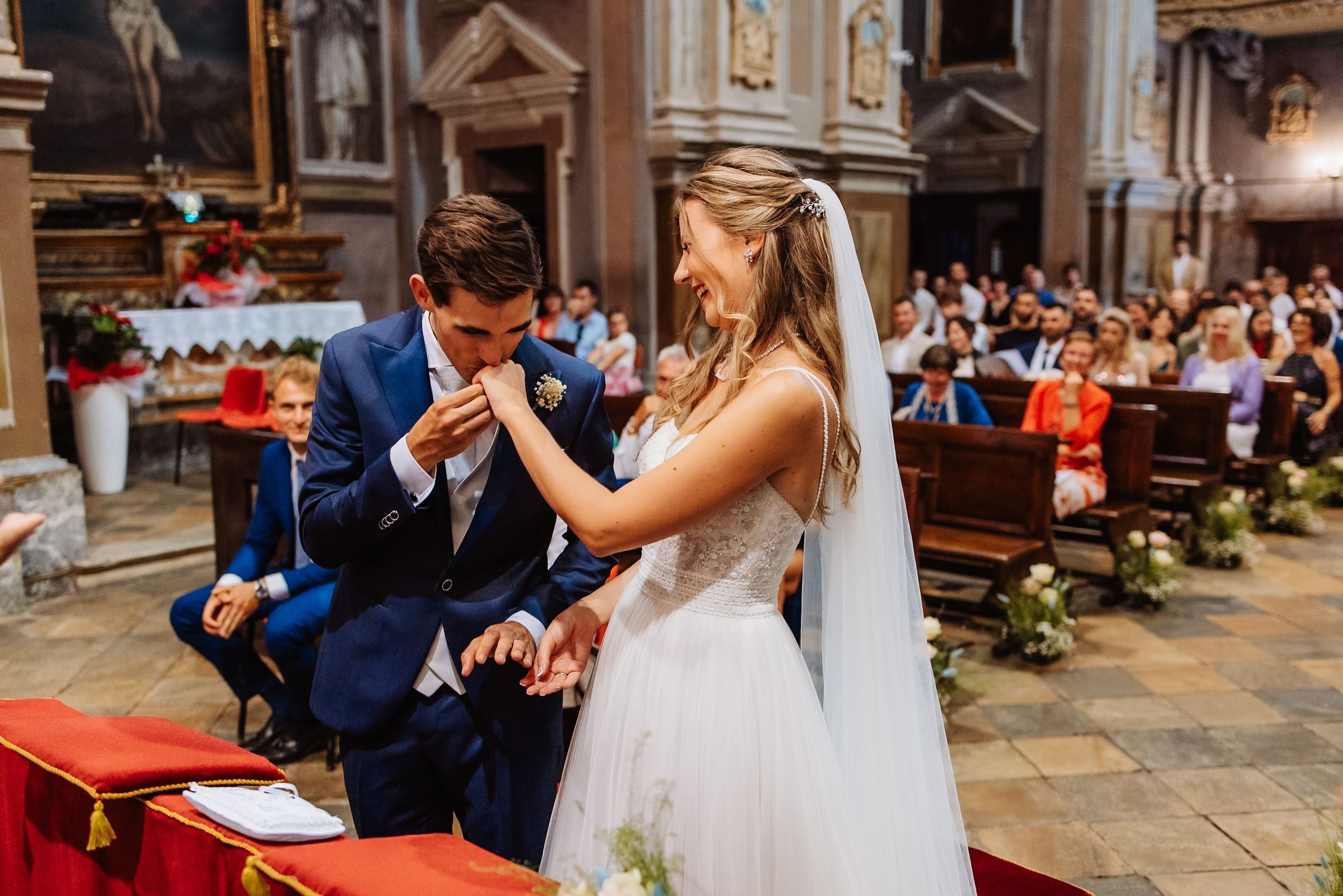 A couple signs their marriage certificate during their church wedding ceremony with an elegant white and red decor.