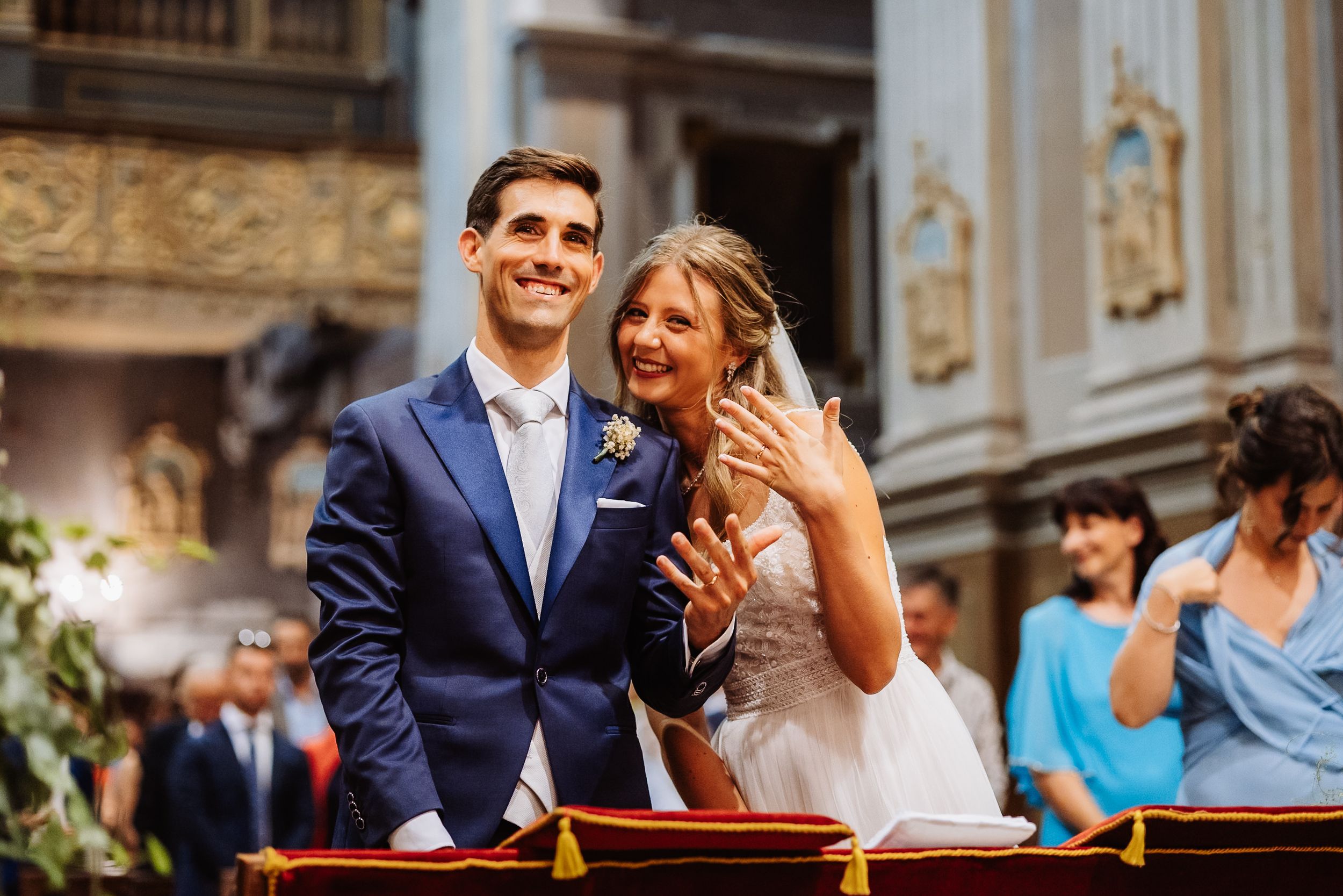 A newlywed couple smiles joyfully during their ornate church wedding ceremony in a traditional setting.