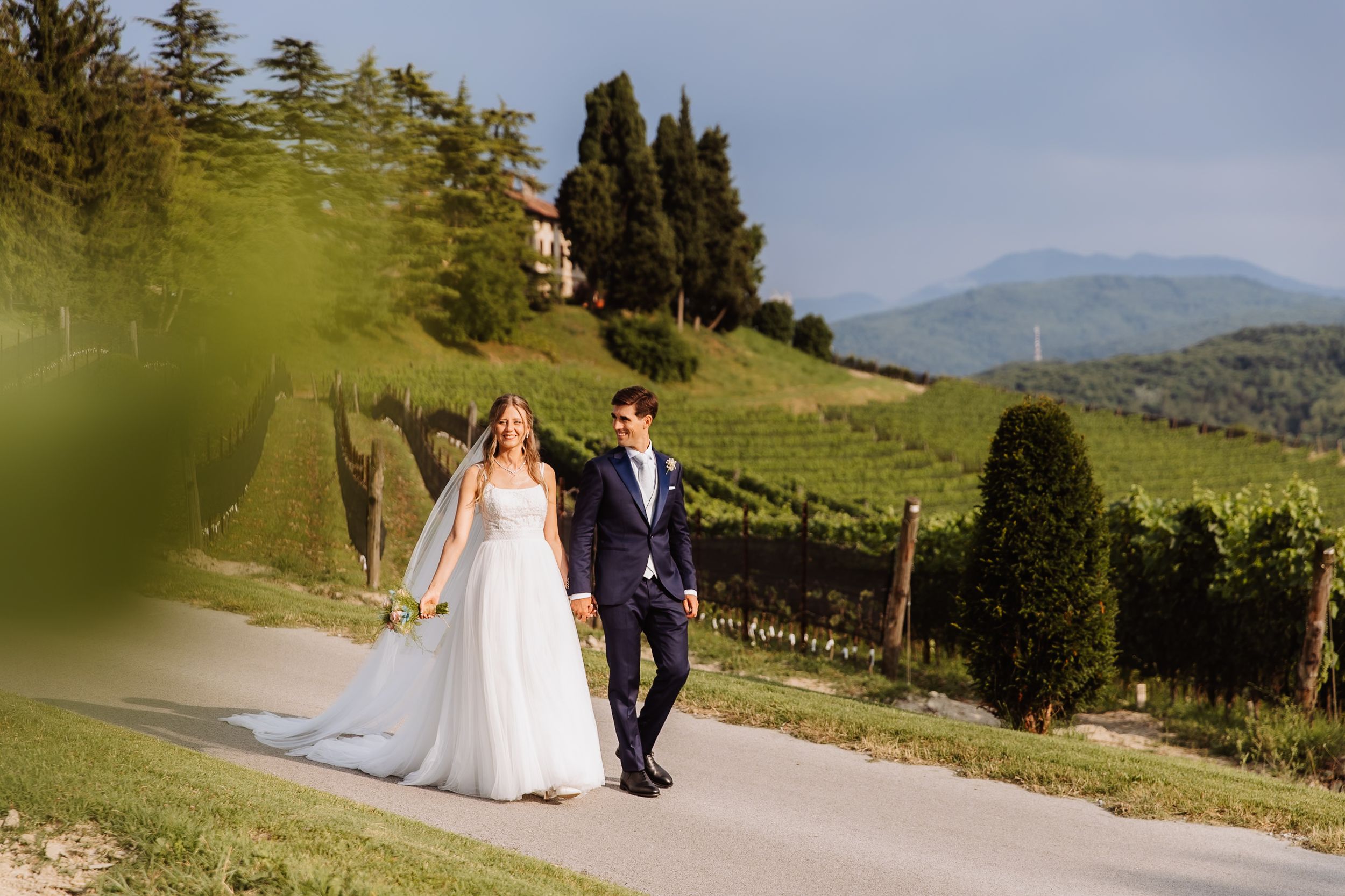Wedding photos showing couple walking together on a scenic mountain path with sweeping alpine landscape views.