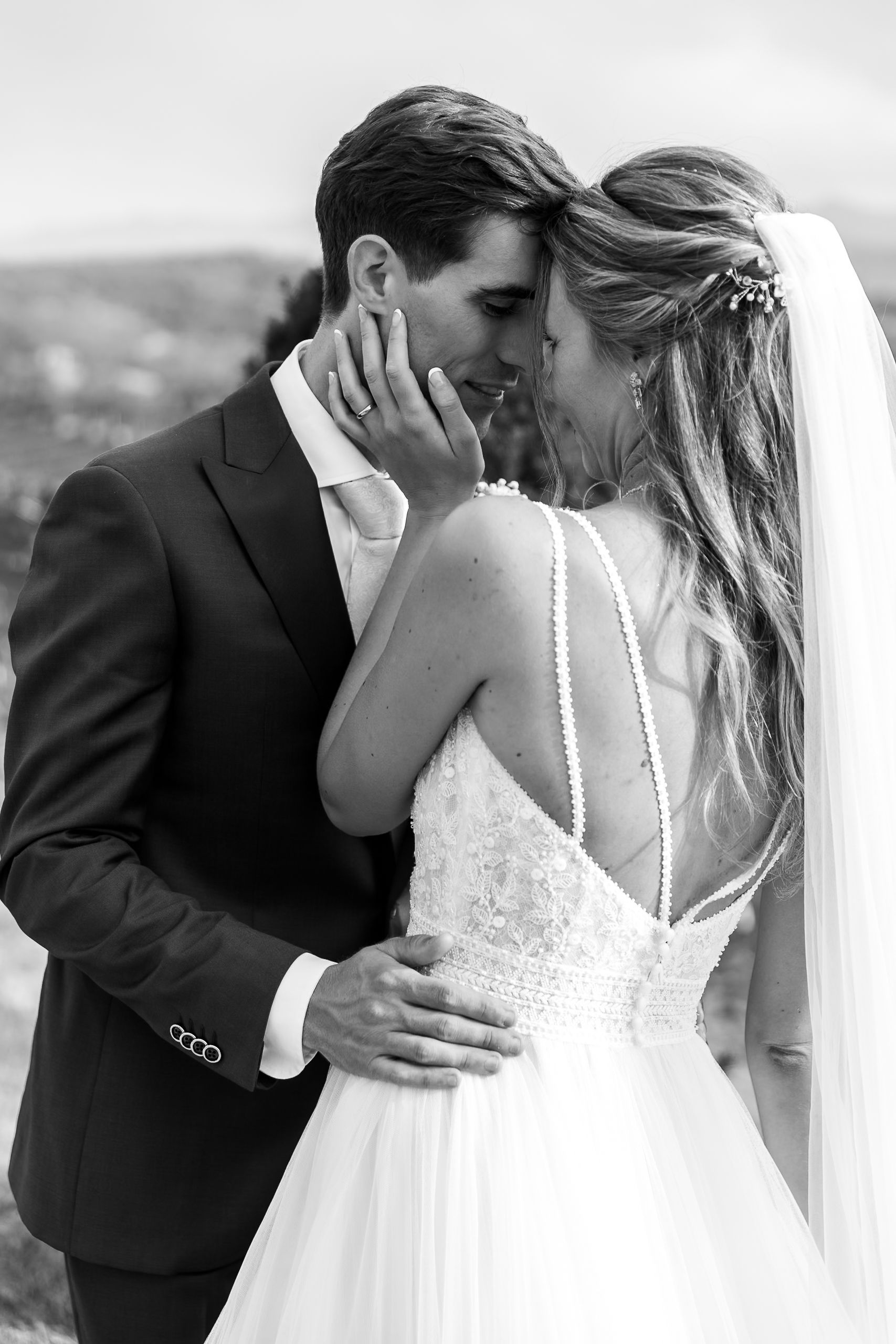 A romantic black and white wedding photo showing an intimate moment between a couple in classic bridal attire.