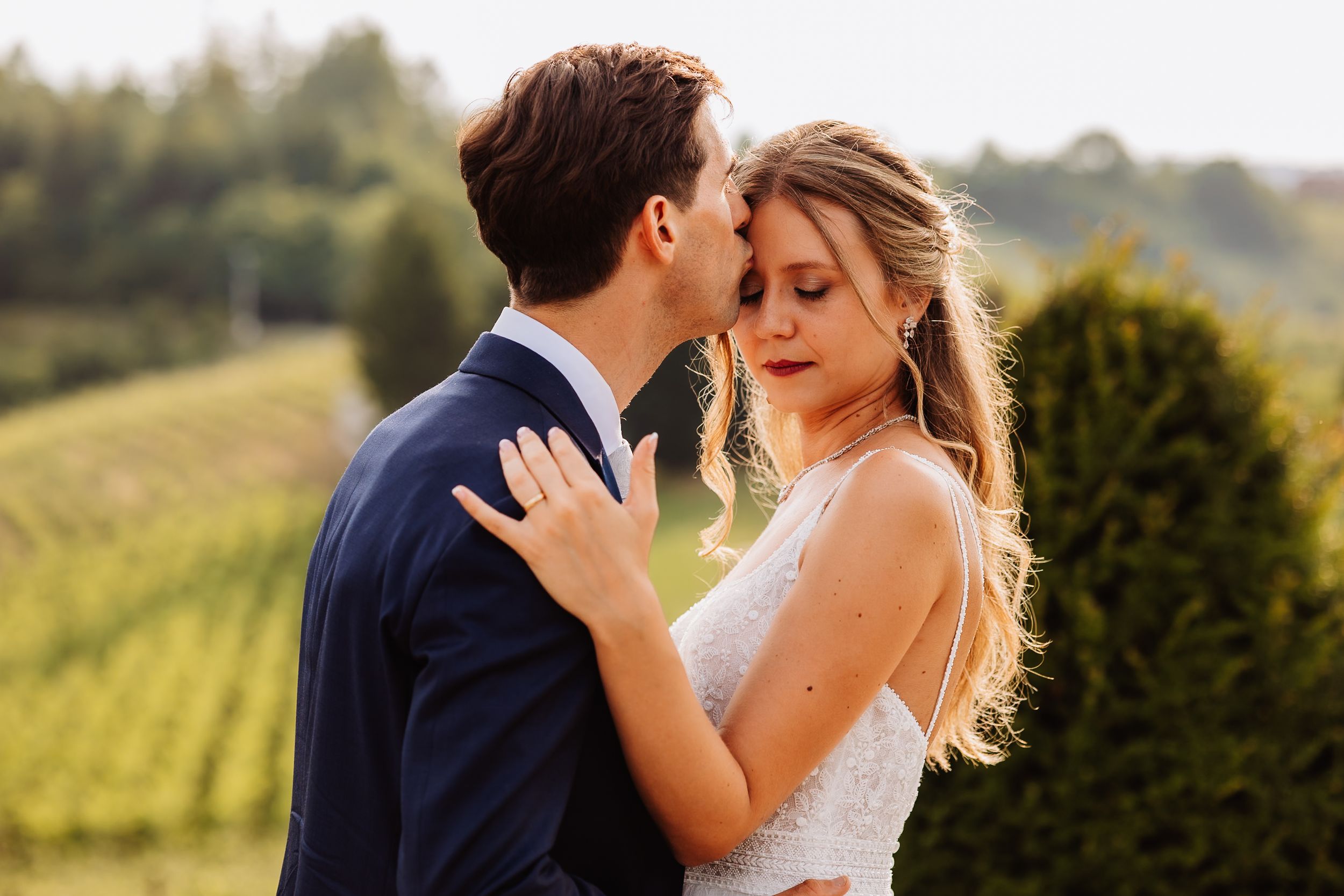 A romantic photo series of newlyweds embracing in a golden sunset at a vineyard setting.