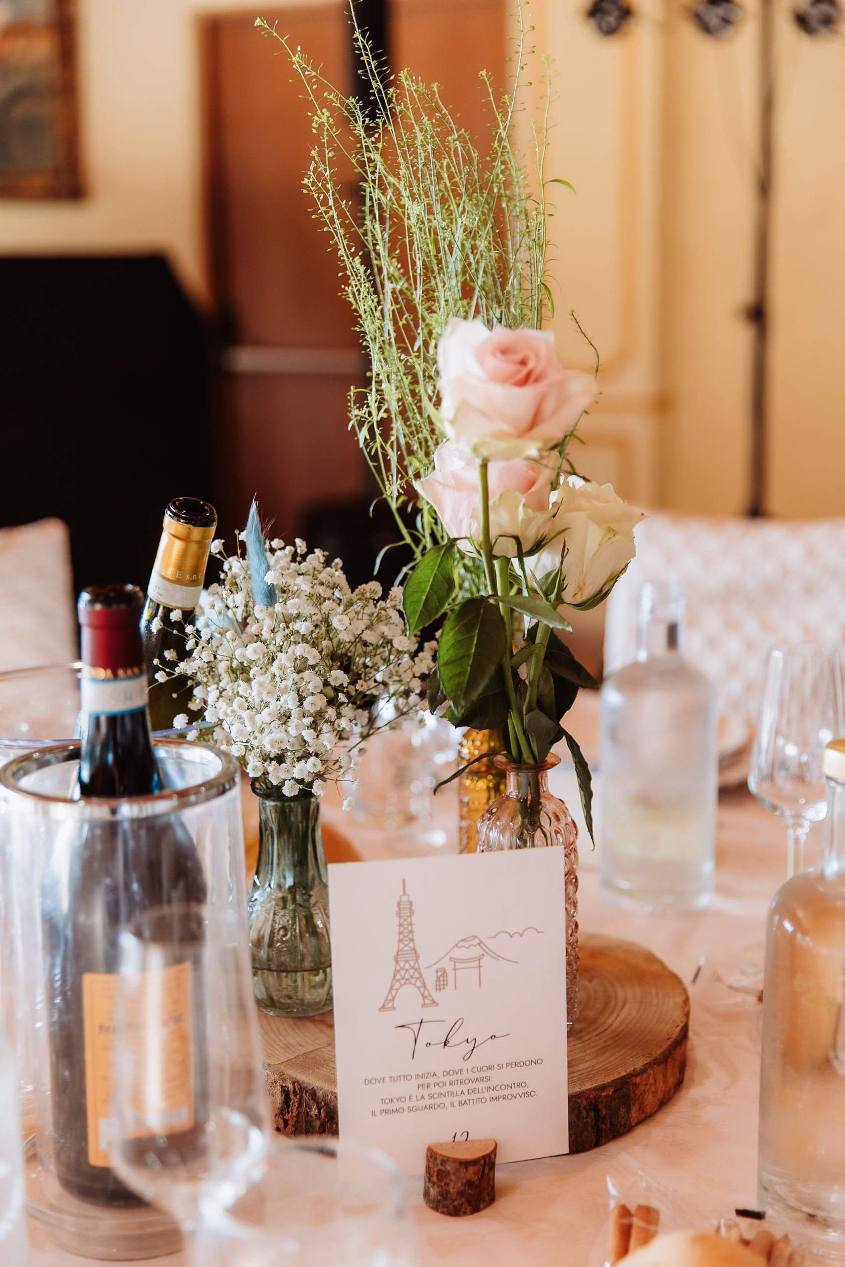 Elegant wedding table settings with vintage bottles, pink roses, baby's breath flowers and name cards create a romantic ambiance.