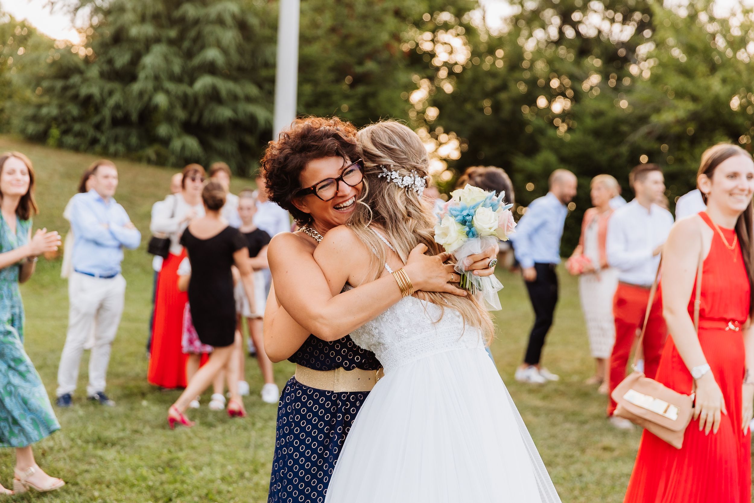 Wedding guests dance and celebrate together outdoors during golden hour at a summer reception.
