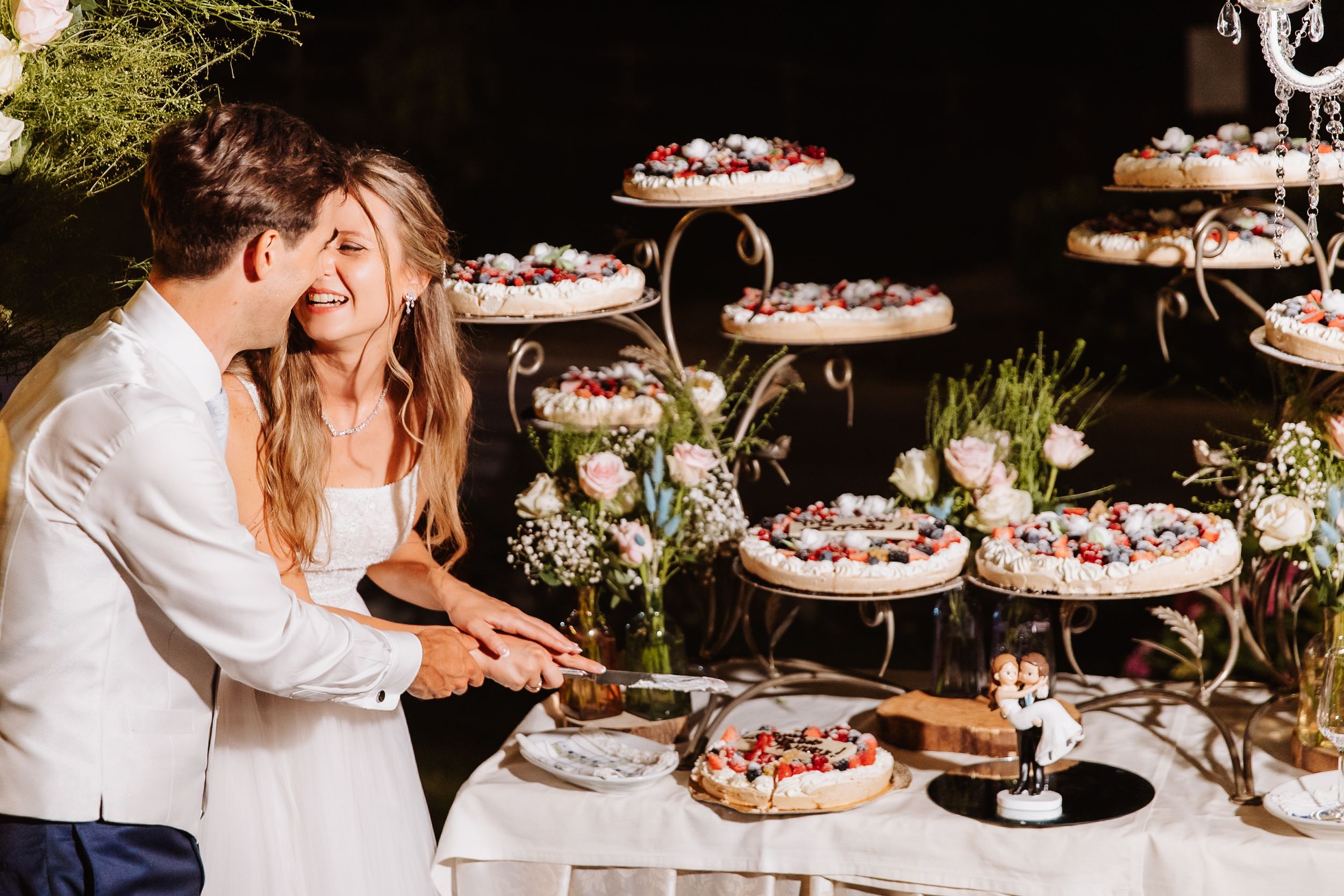 Elegant wedding dessert table with tiered cakes and delicate floral decorations in outdoor setting.