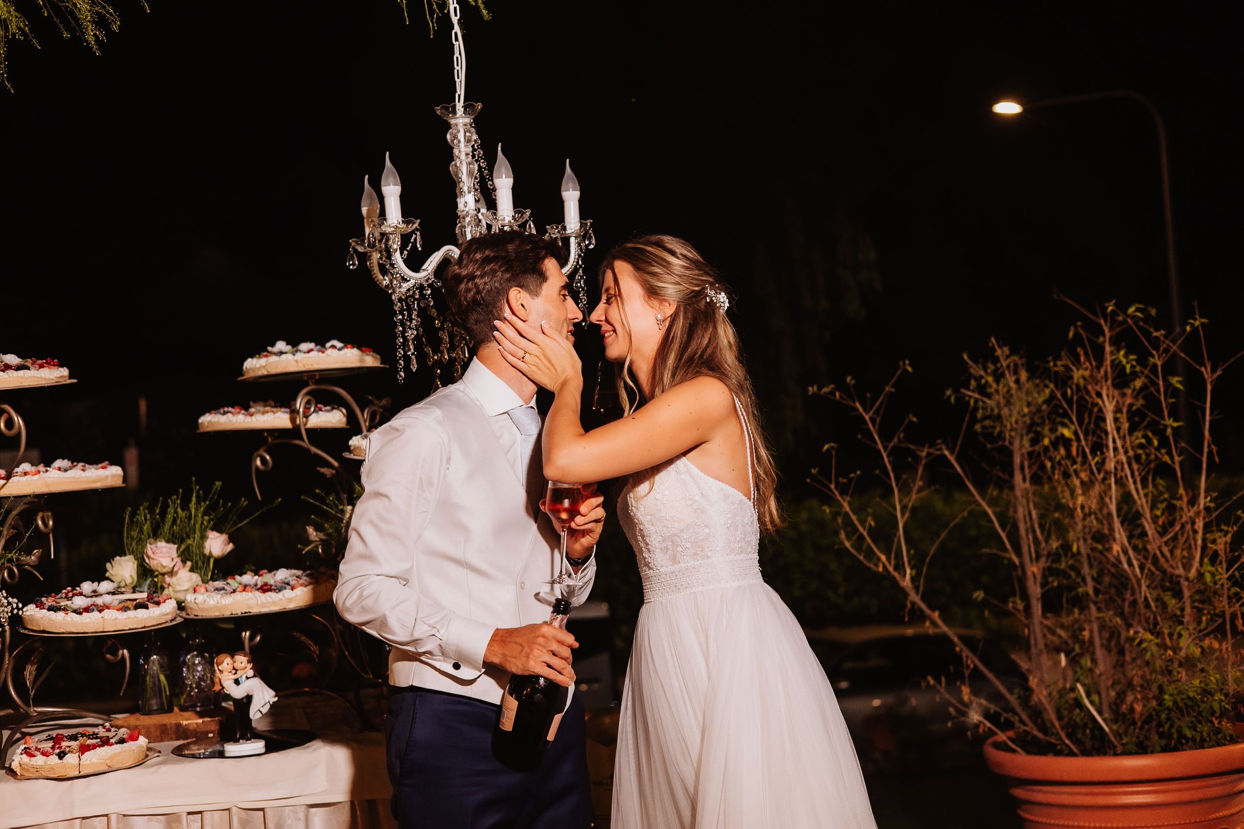 An intimate nighttime wedding moment beside a tiered display of desserts under moonlight.