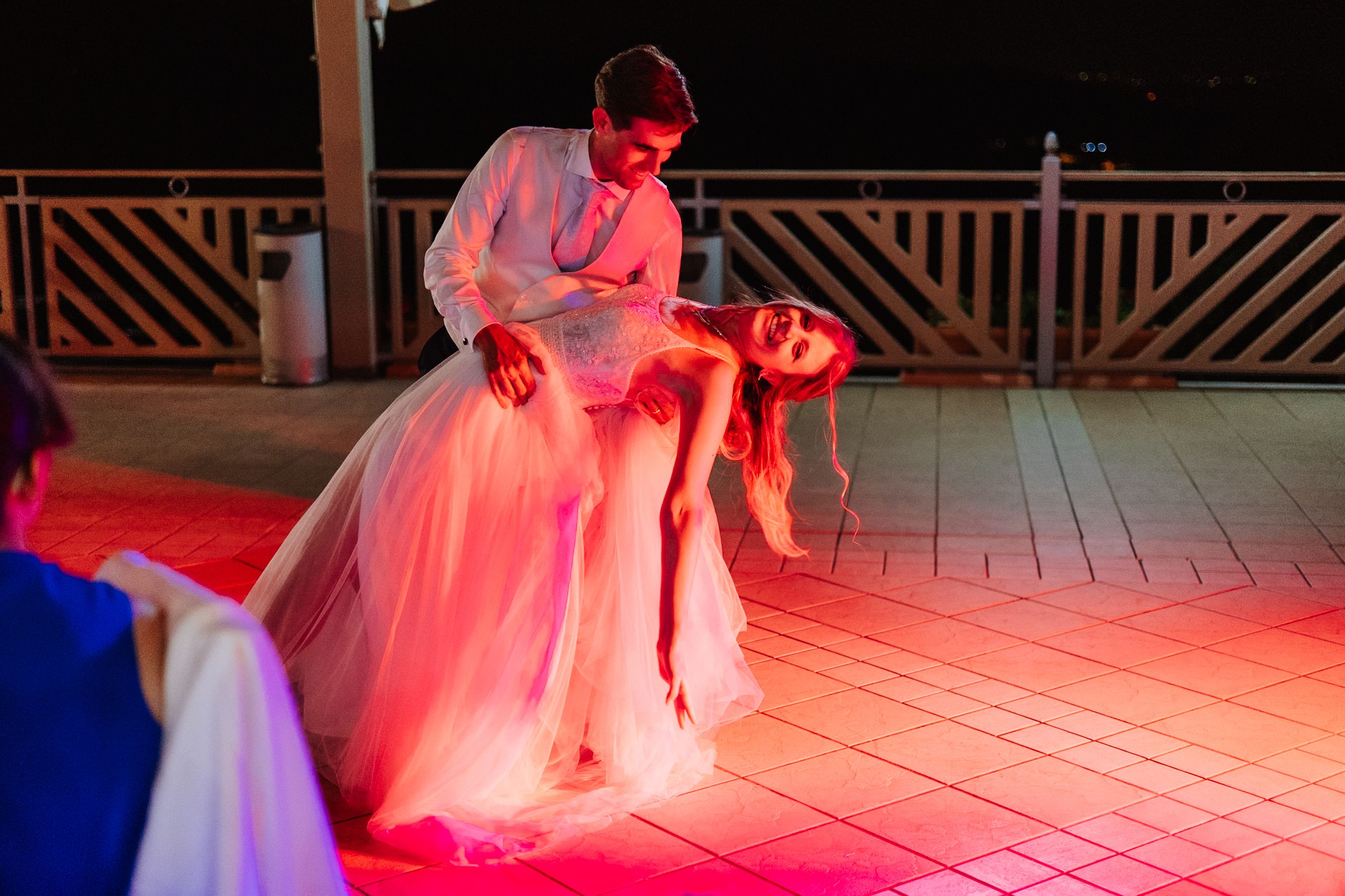 Dance floor illuminated with red lighting at an evening wedding reception.