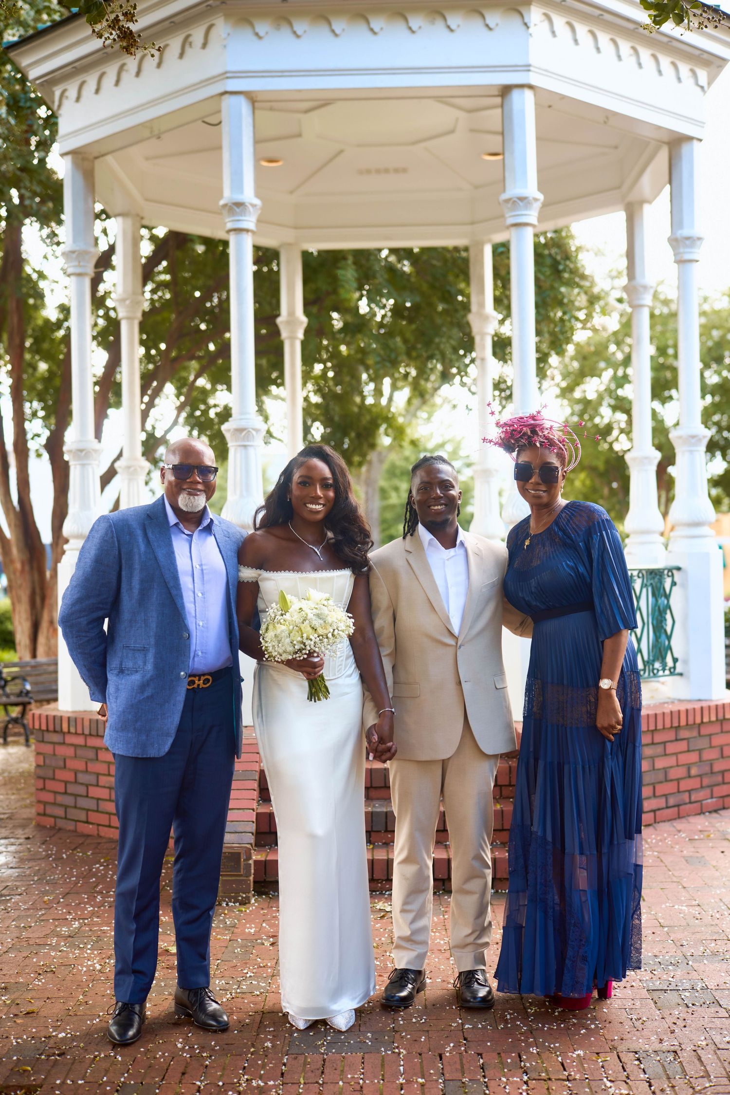 Family members gather under a white gazebo wearing coordinated blue and white formal attire for wedding portraits.