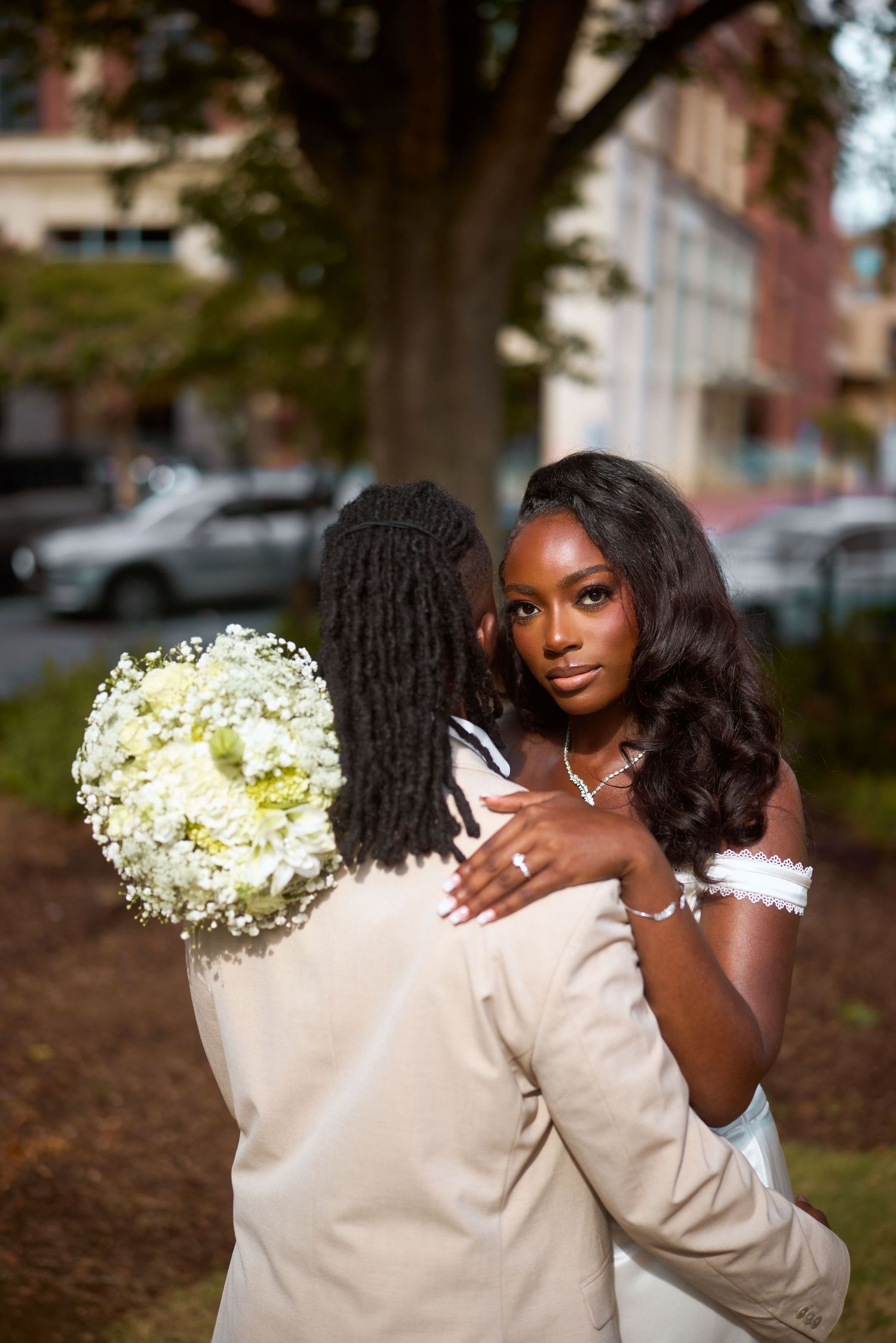 Two people wearing beige outfits pose creatively with white hydrangea flowers during an outdoor autumn photo session.