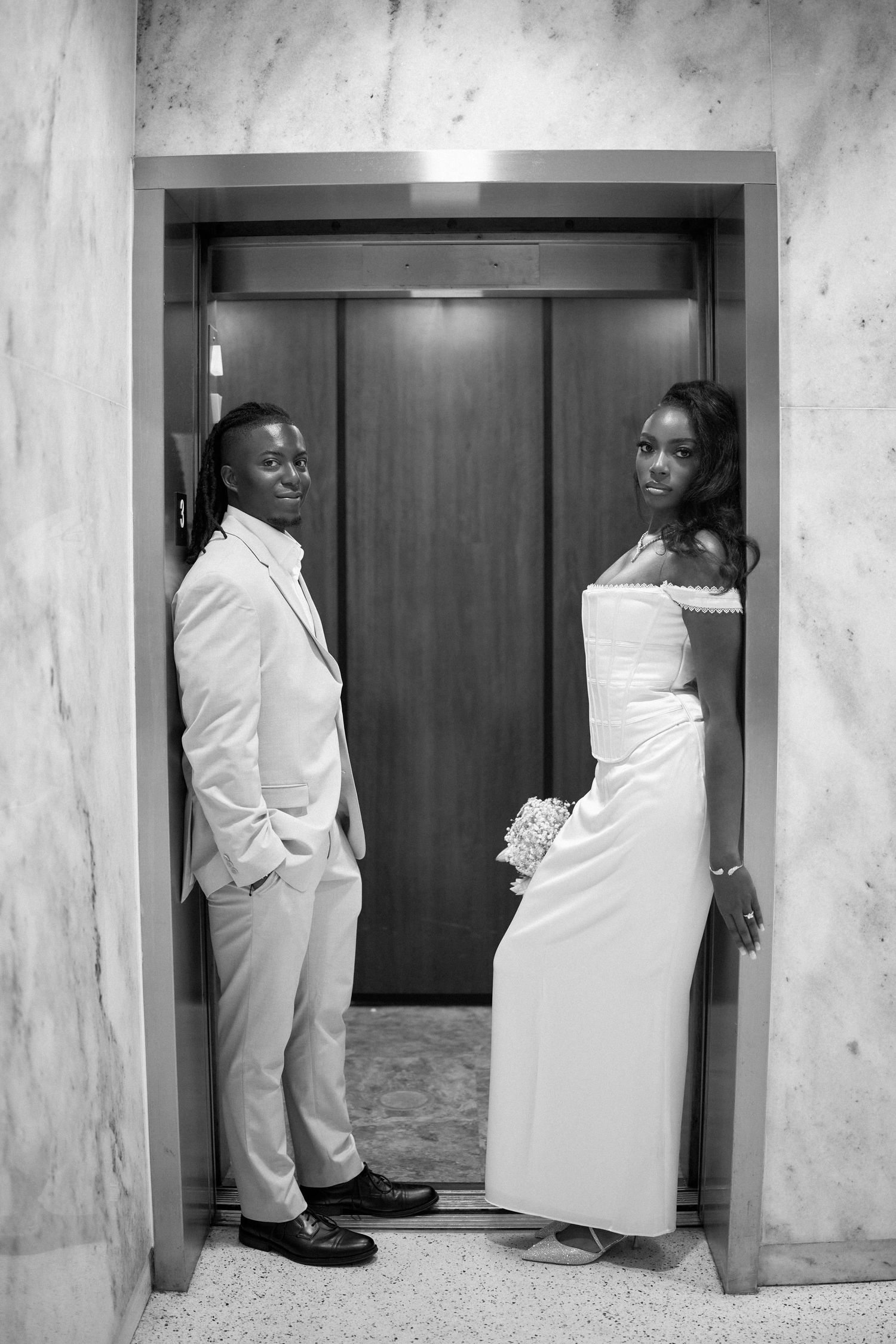 Black and white sequence showing playful interactions in a hallway by an elevator door.