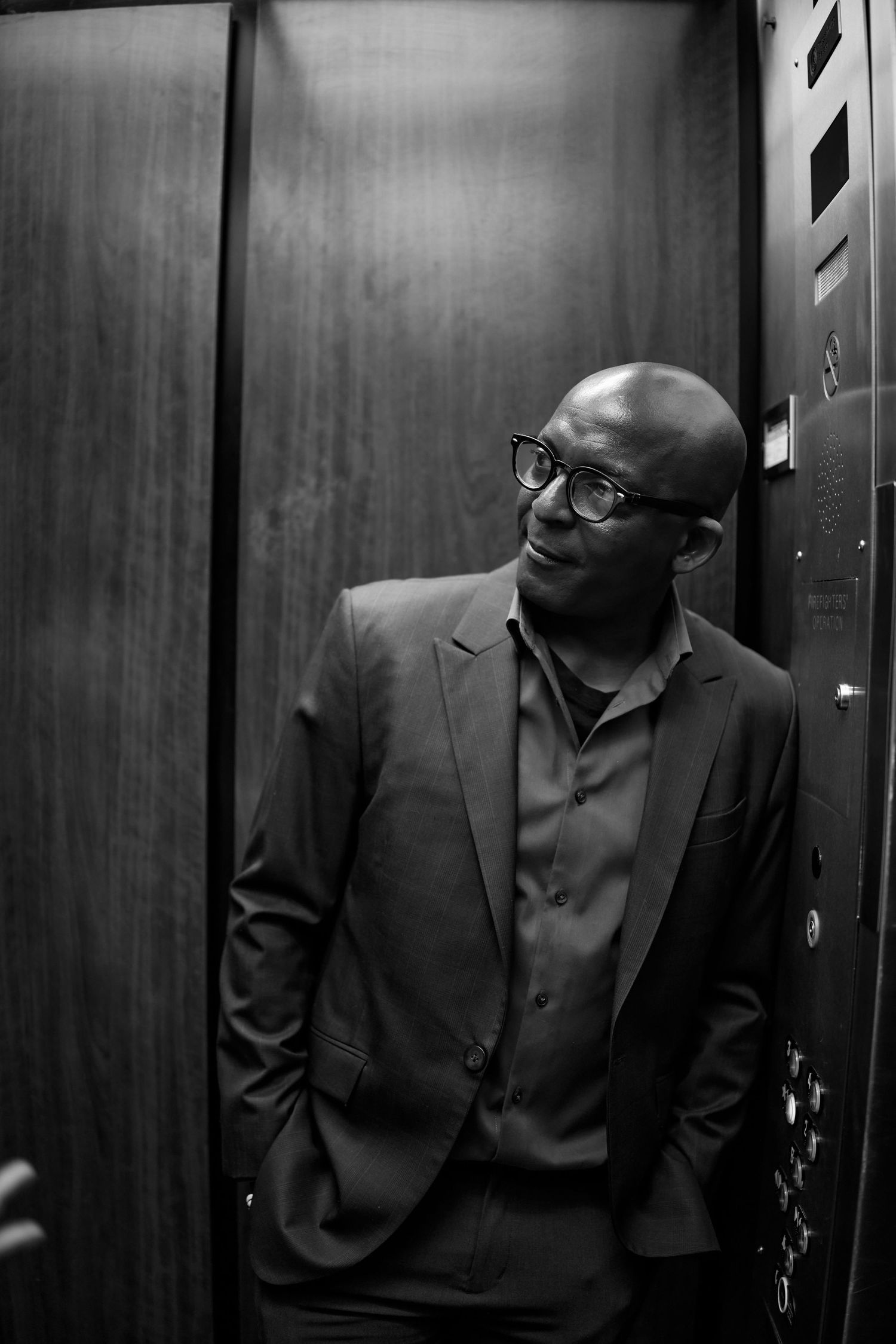 A sequence of black and white elevator photos shows a person in formal attire looking down while riding.