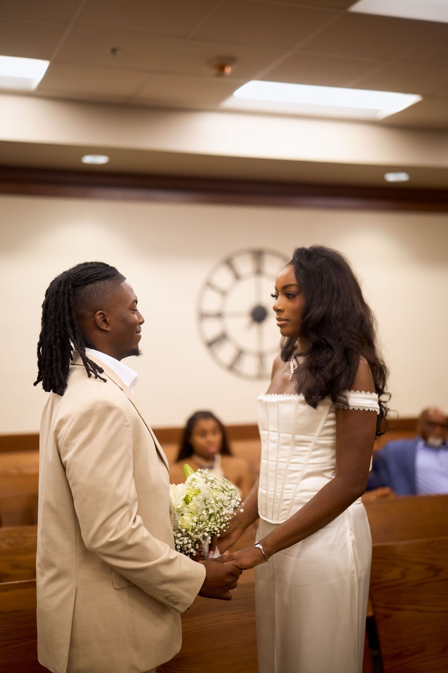 A couple shares an intimate moment during their wedding ceremony in a warmly lit church with wooden pews.