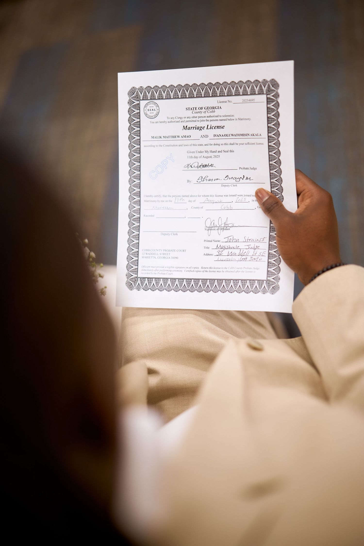 A close-up shot of hands holding a graduation certificate or diploma with an ornate border pattern.