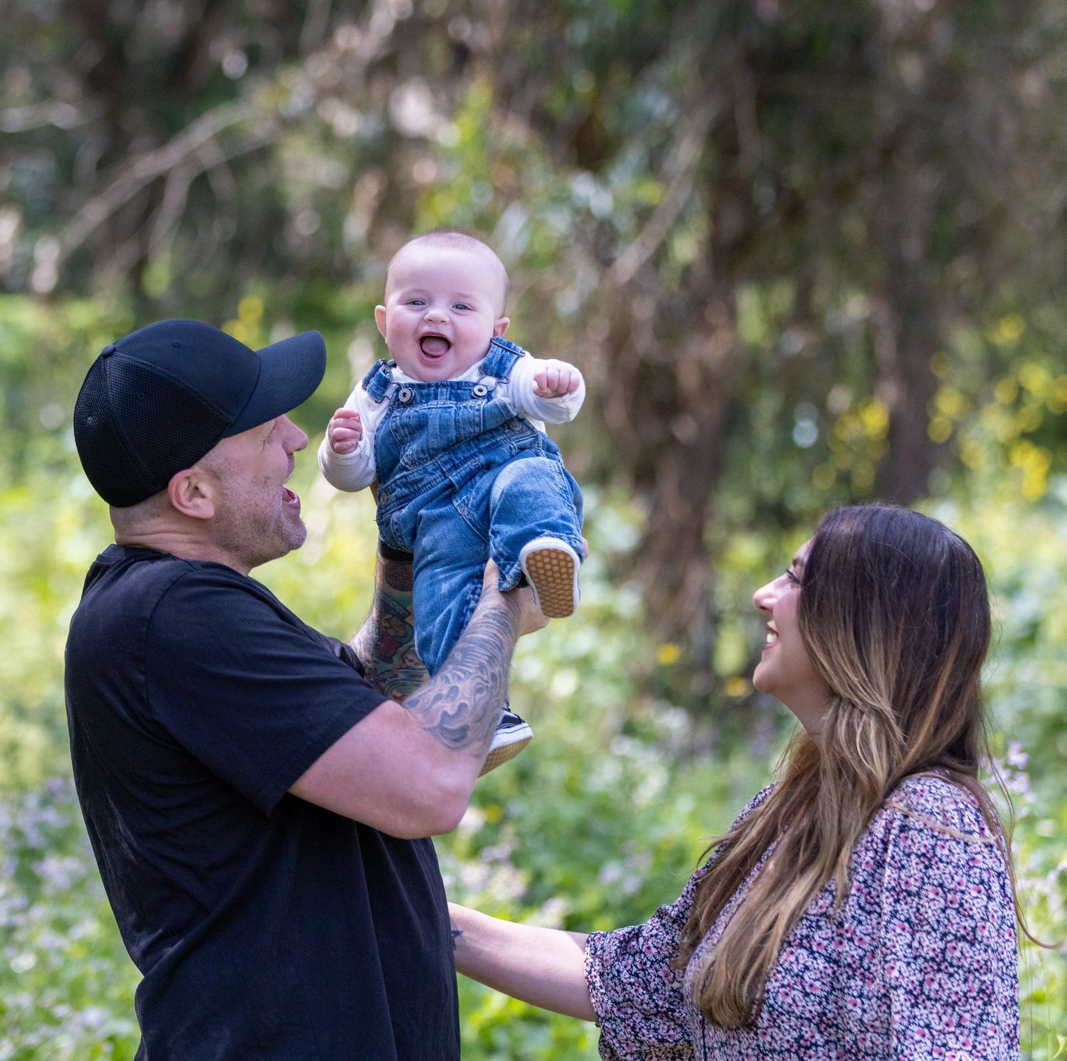 Family enjoying playful moments together in an outdoor setting with natural greenery in the background.