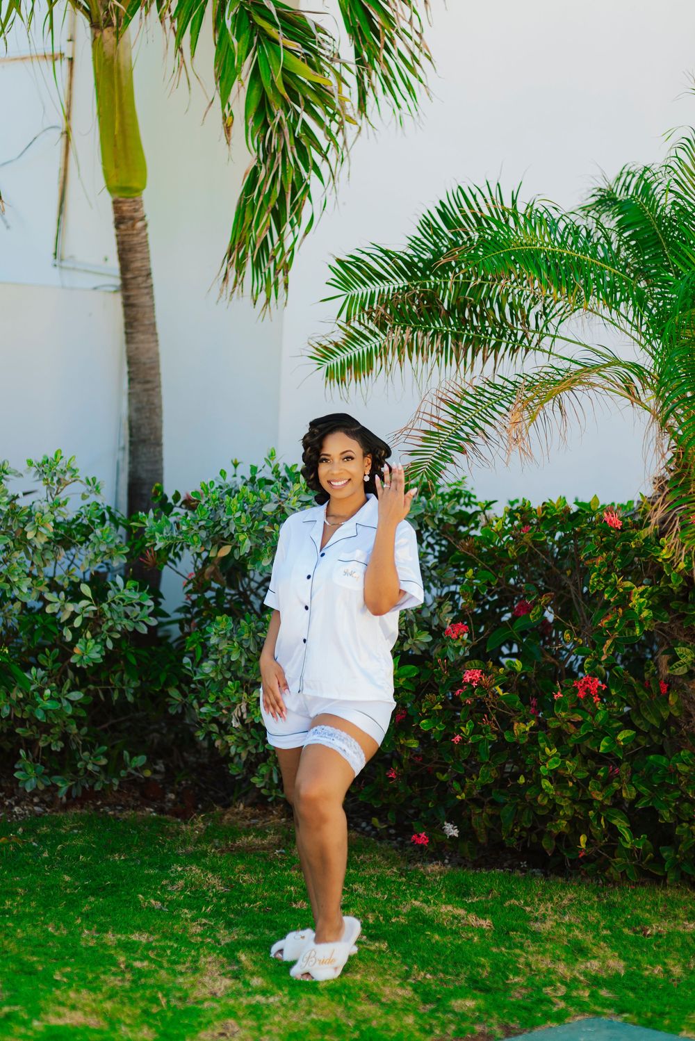 Playful outdoor photoshoot in front of palm trees and flowering bushes.
