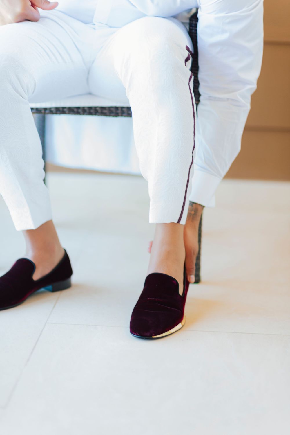 Close-up view of black suede loafers with white pants showing elegant footwear styling details.