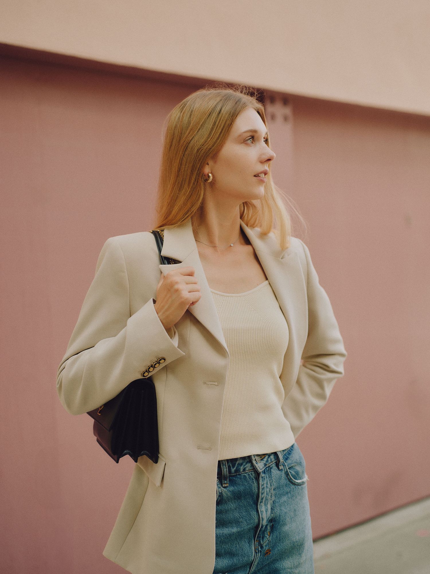 A woman in a gray blazer poses against a blue curtain backdrop in a professional photoshoot.