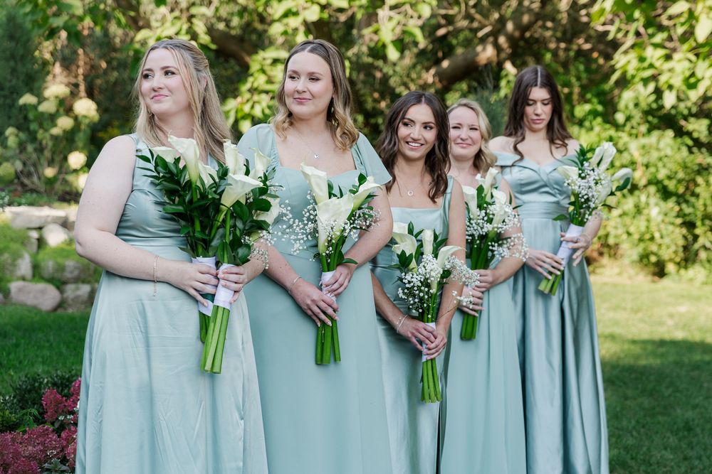 Bridesmaids in mint green dresses looking at the bride and groom during ceremony at The Wren House in St. Jacobs, Ontario.