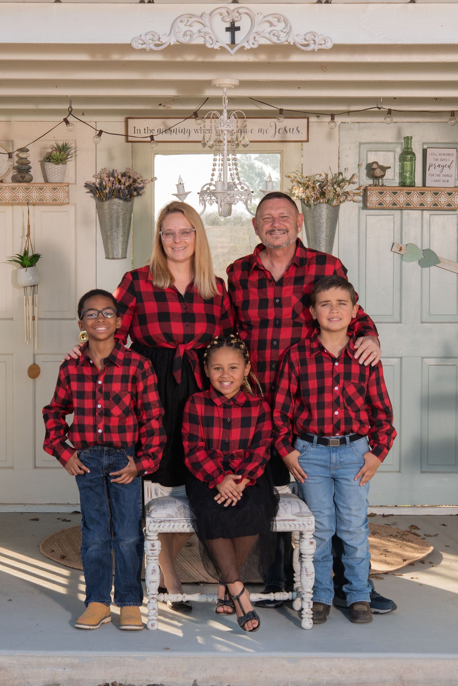 Series of couples and families photographed on a rustic farmhouse porch in matching red and black buffalo plaid outfits.