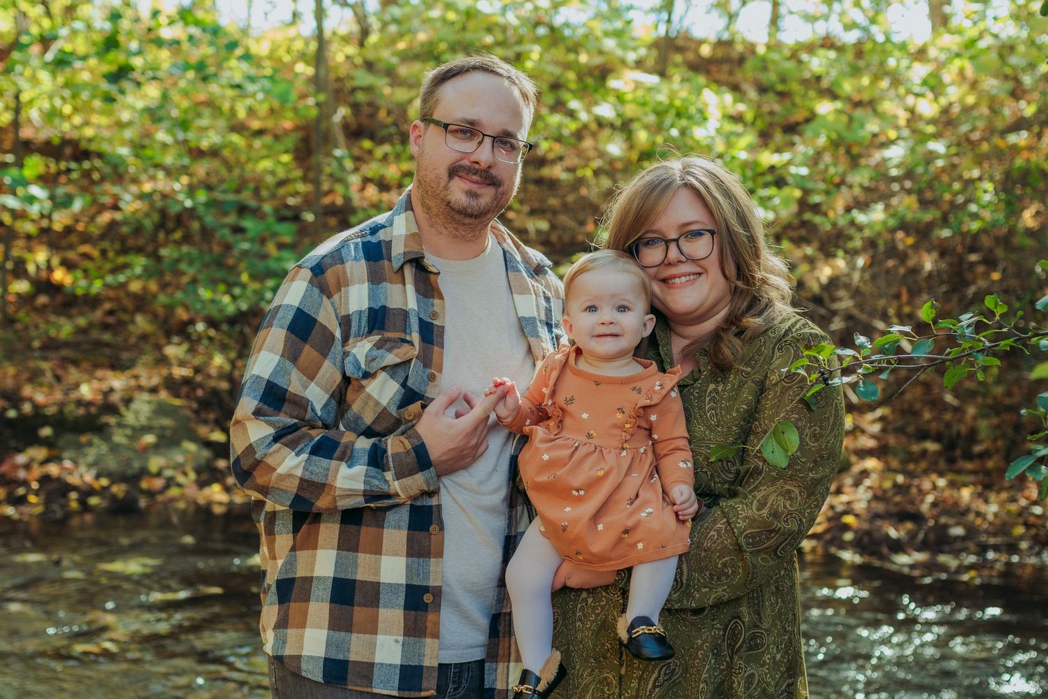 Family enjoying a fall photoshoot outdoors with autumn foliage in the background.