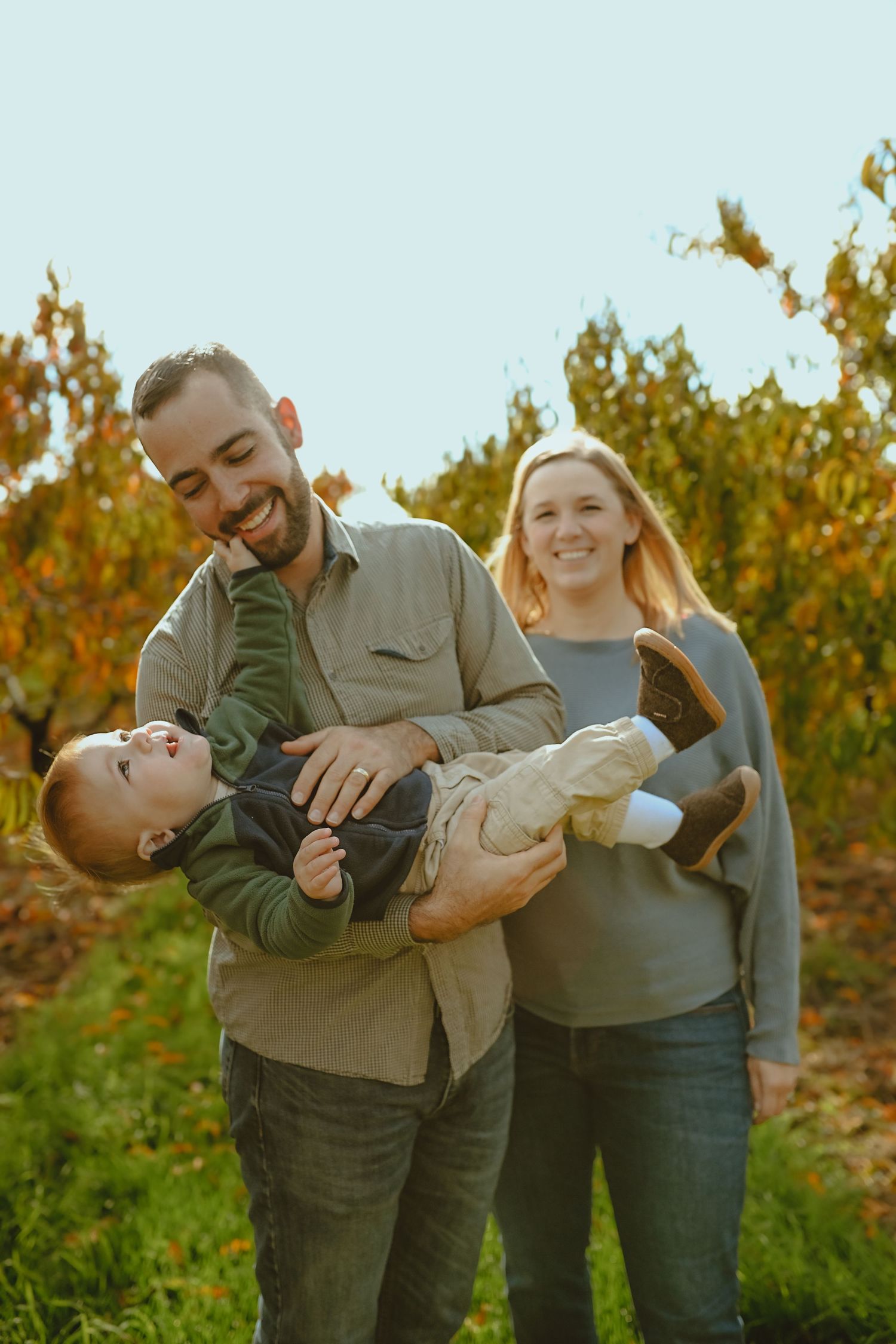 A couple shares playful moments together in an autumn vineyard with golden sunlight filtering through the vines.