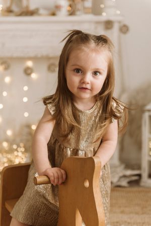 A holiday themed portrait with a gold metallic dress and warm twinkle lights in the background.