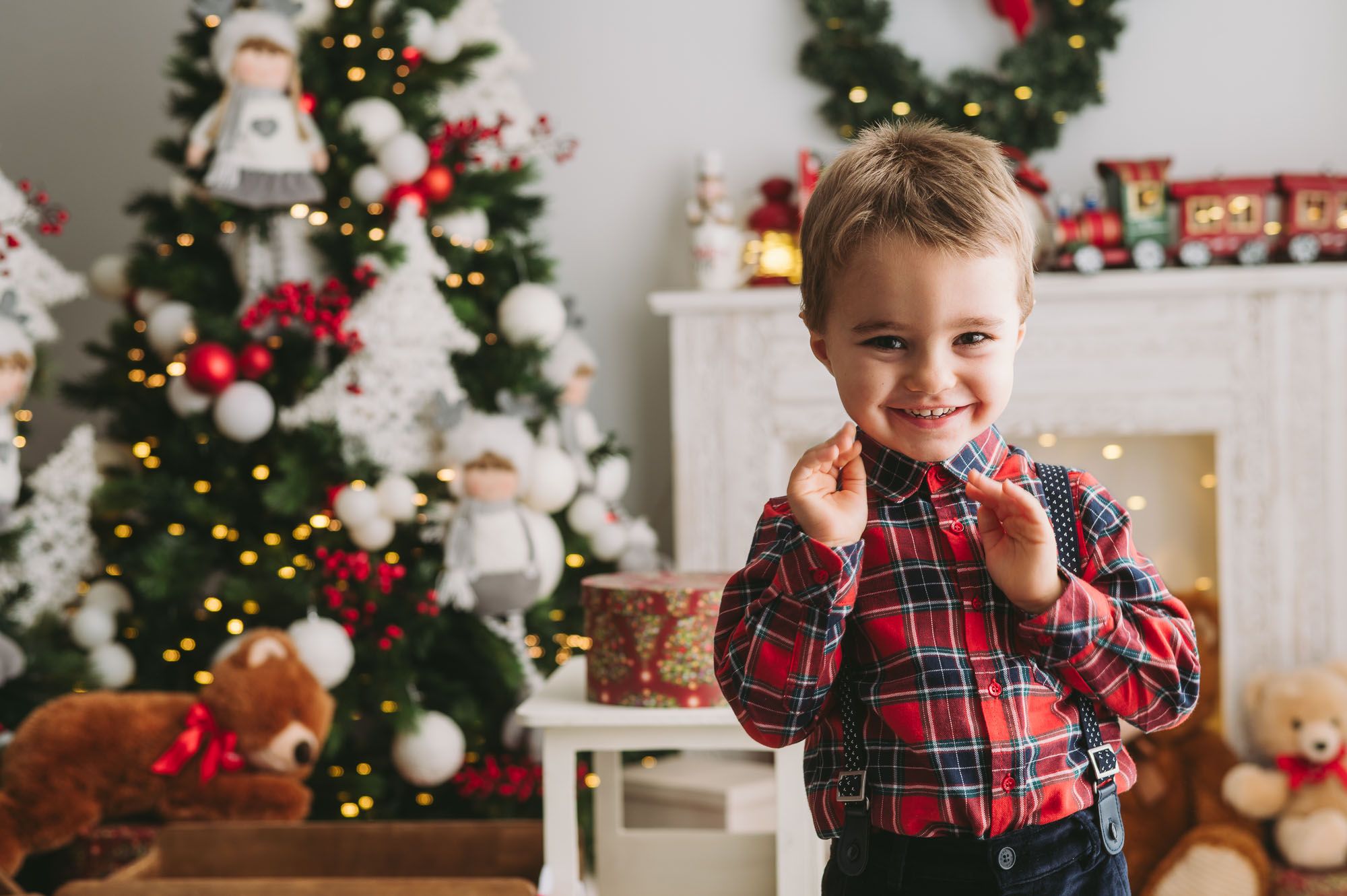 Holiday portrait by Christmas tree with decorated mantel and wreath.