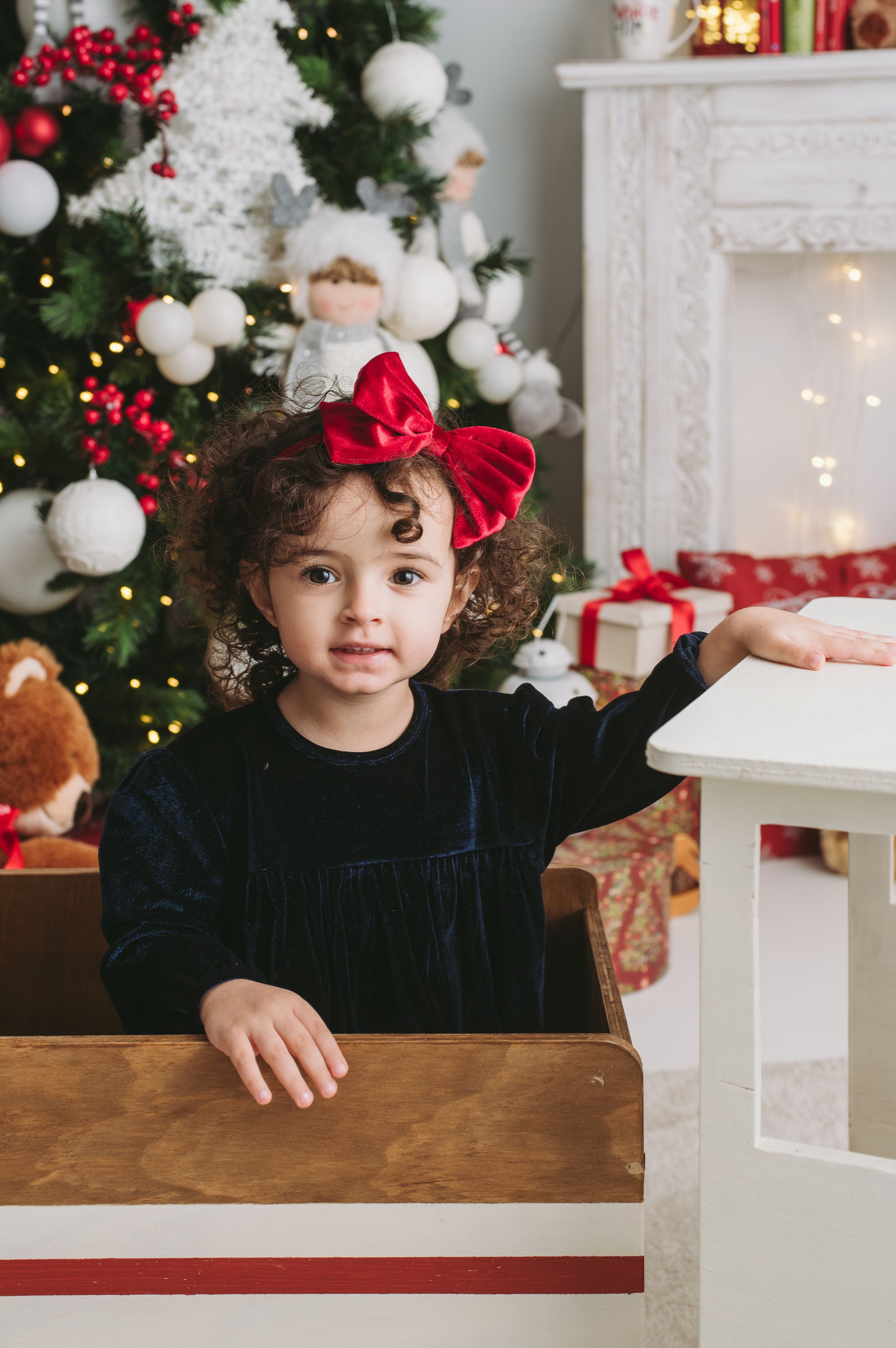 Holiday portrait in front of decorated Christmas tree and white fireplace.