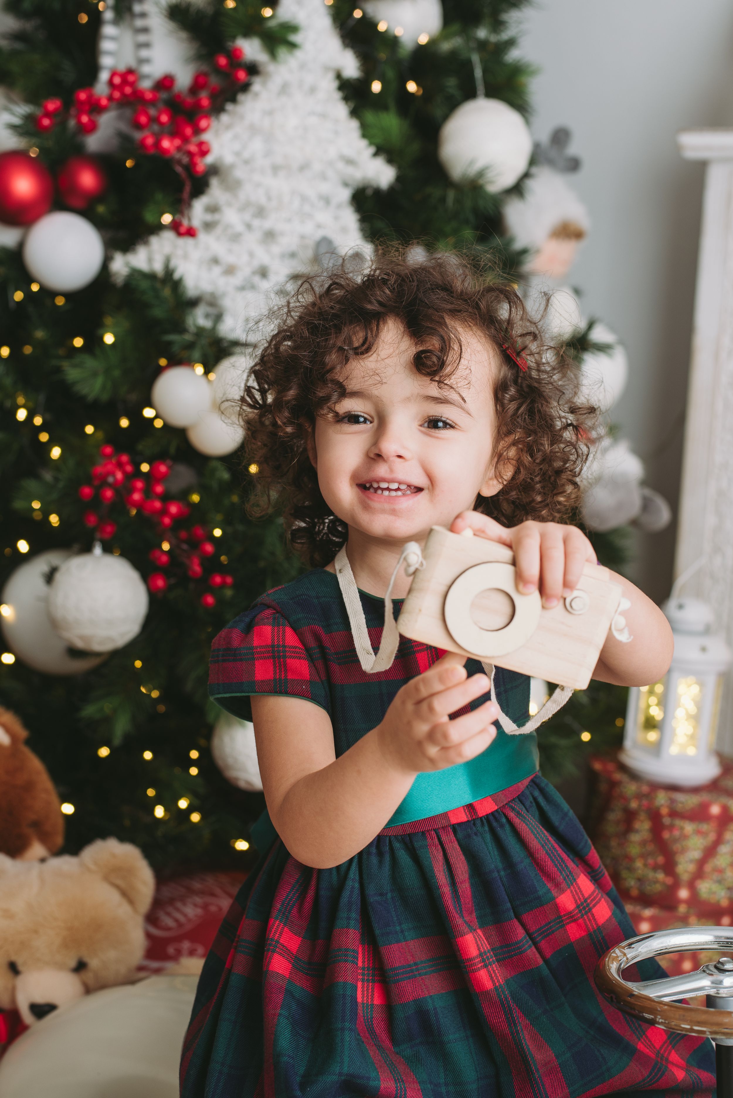 Festive holiday photo with plaid dress and wooden toy train.