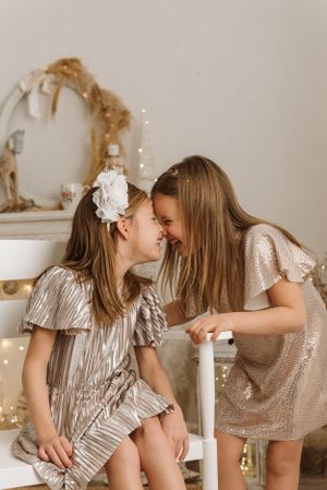 Two children sharing a happy moment in festive holiday outfits with twinkle lights.