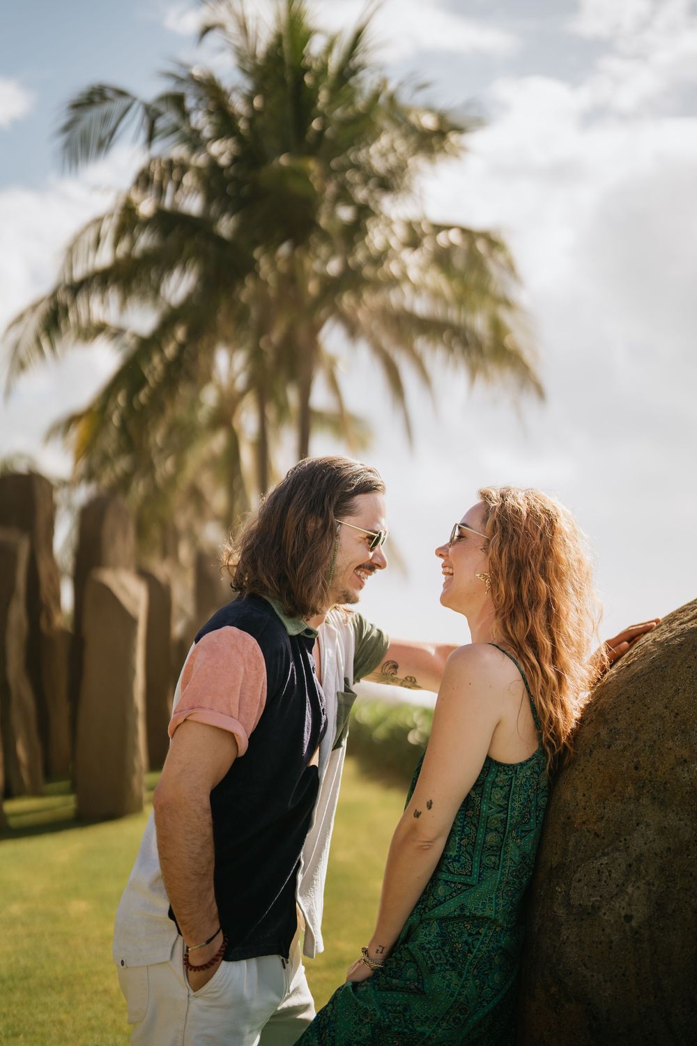 A couple shares a tender moment near palm trees in golden afternoon light.